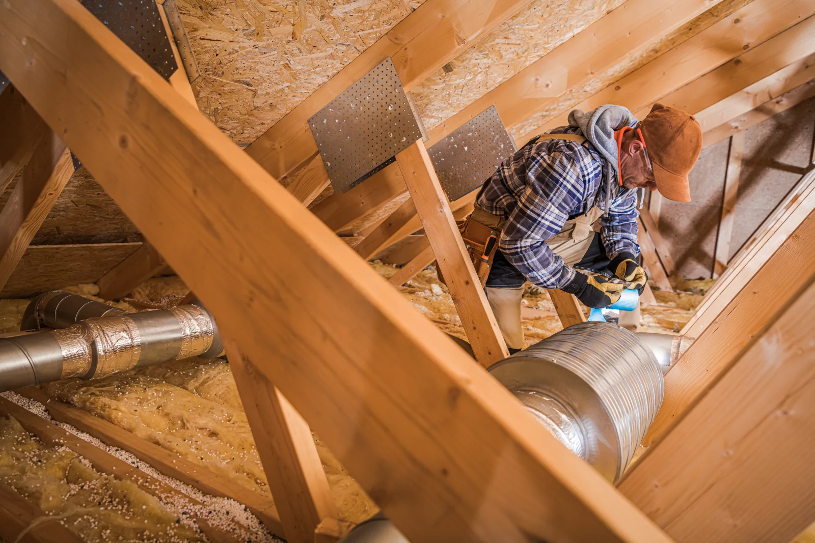 An HVAC technician connecting insulated ductwork in a Phoenix home's attic as part of a new furnace installation.