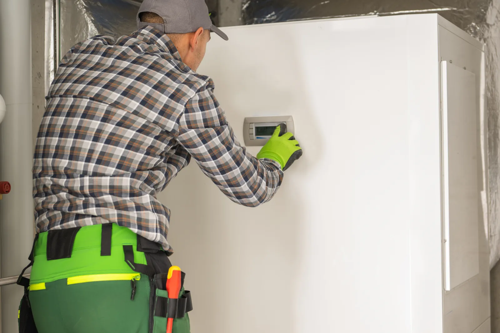 An HVAC technician programming the control panel on a newly installed furnace during startup and testing.