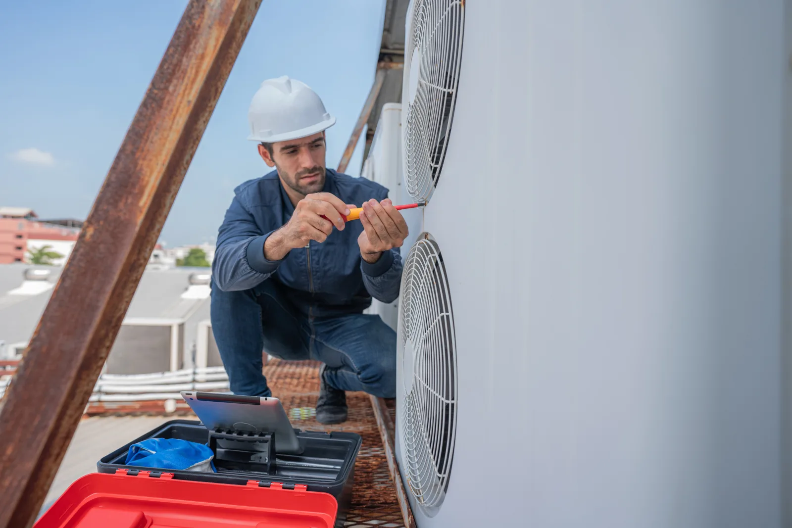phoenix-hvac-repair Phoenix HVAC — a licensed technician in a branded uniform servicing a rooftop air conditioning unit.