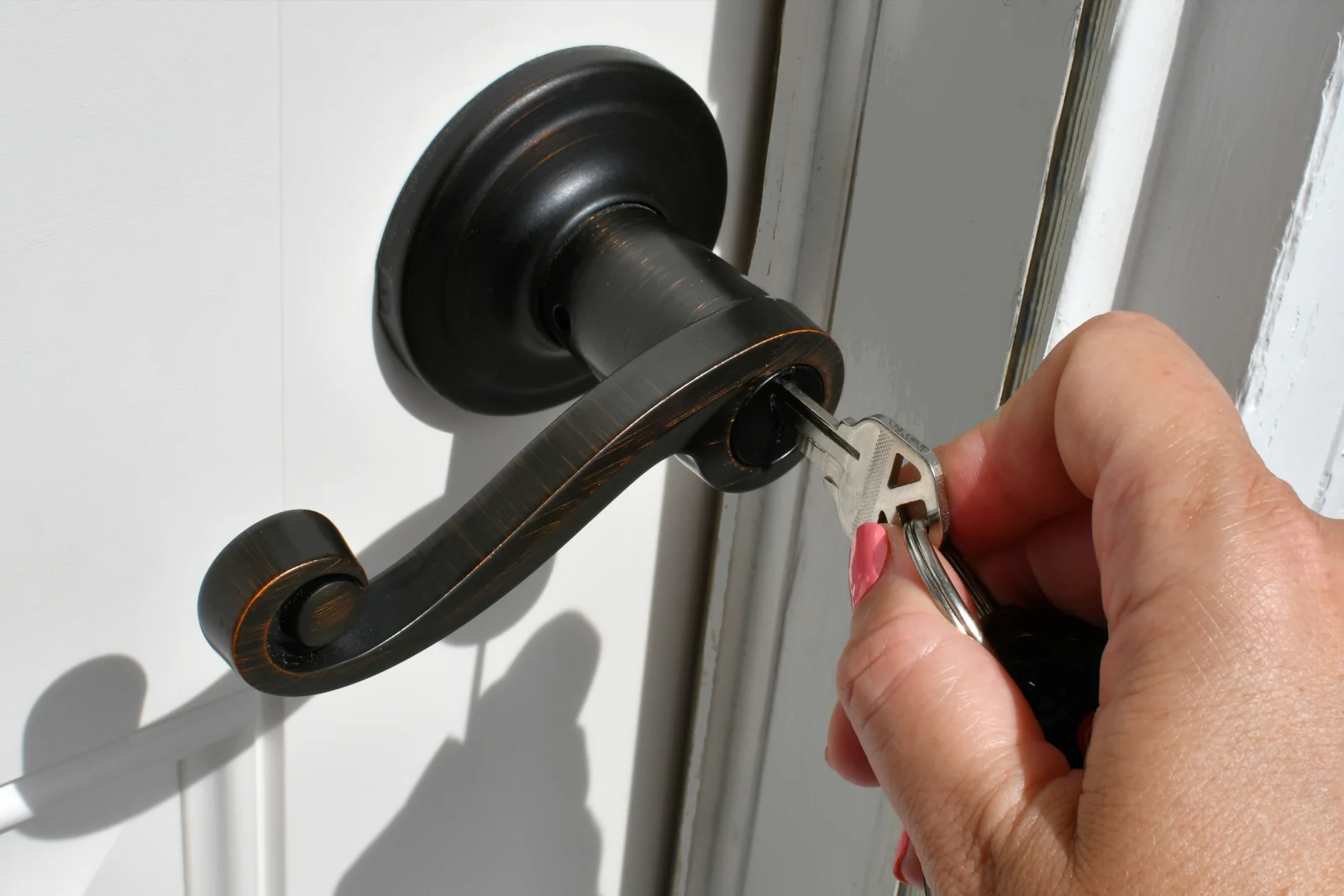 Phoenix lock repair — a hand turning a key in an oil-rubbed bronze lever handle door lock.