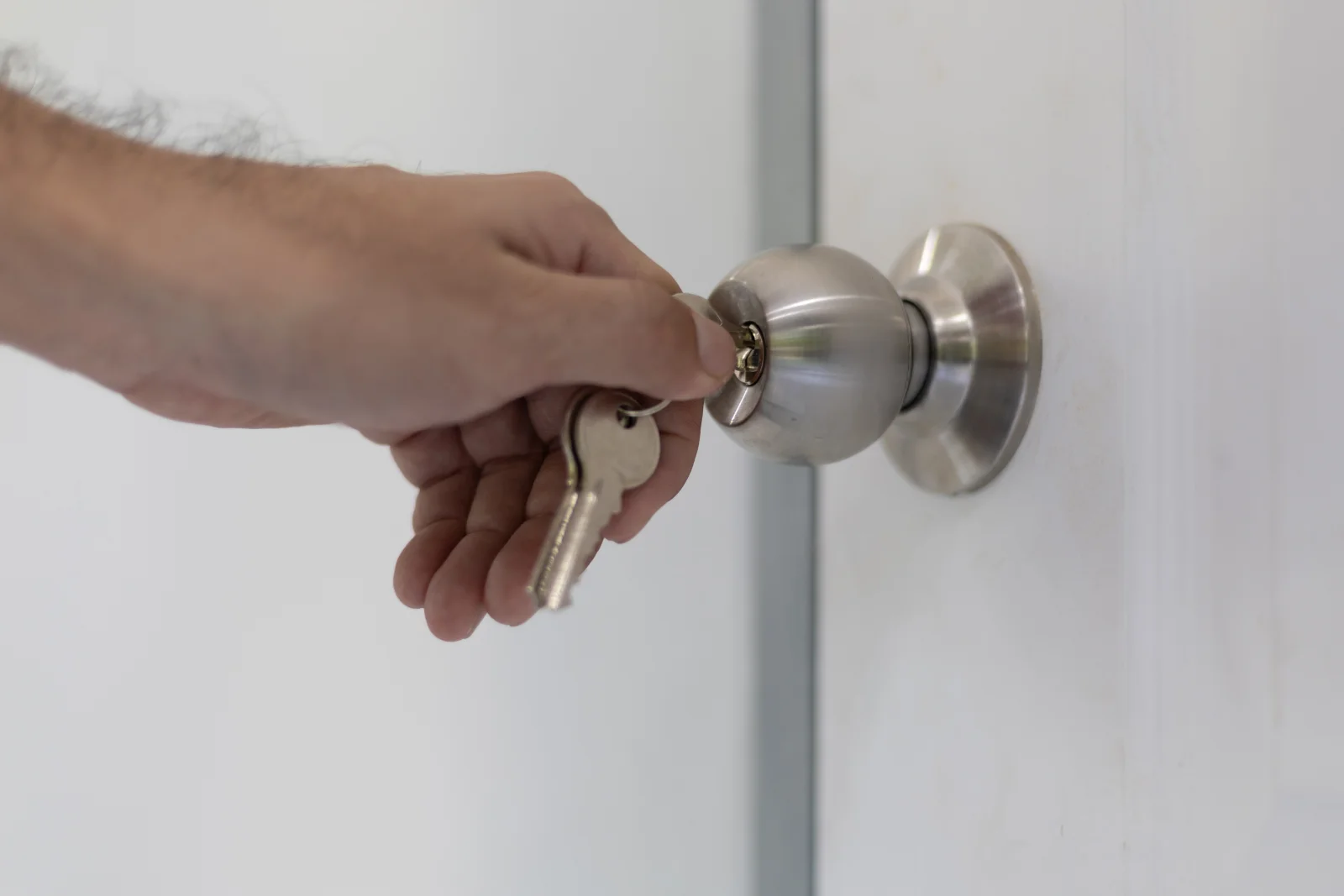 Phoenix lock repair — a hand inserting a key into a round doorknob lock on a residential door.