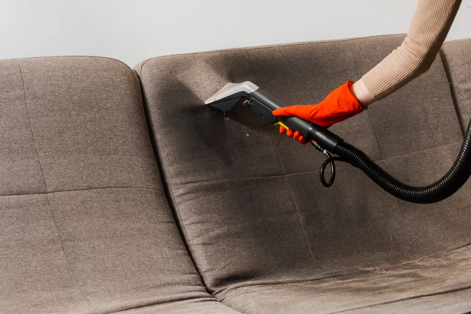 A gloved technician using a fabric extraction tool to deep clean a sofa cushion in Phoenix, Arizona.