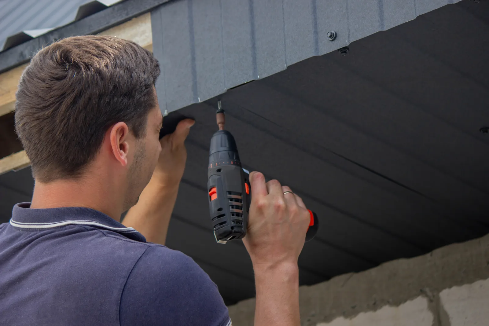 Phoenix wildlife removal — a technician sealing a wildlife entry point along a roofline with a power drill.