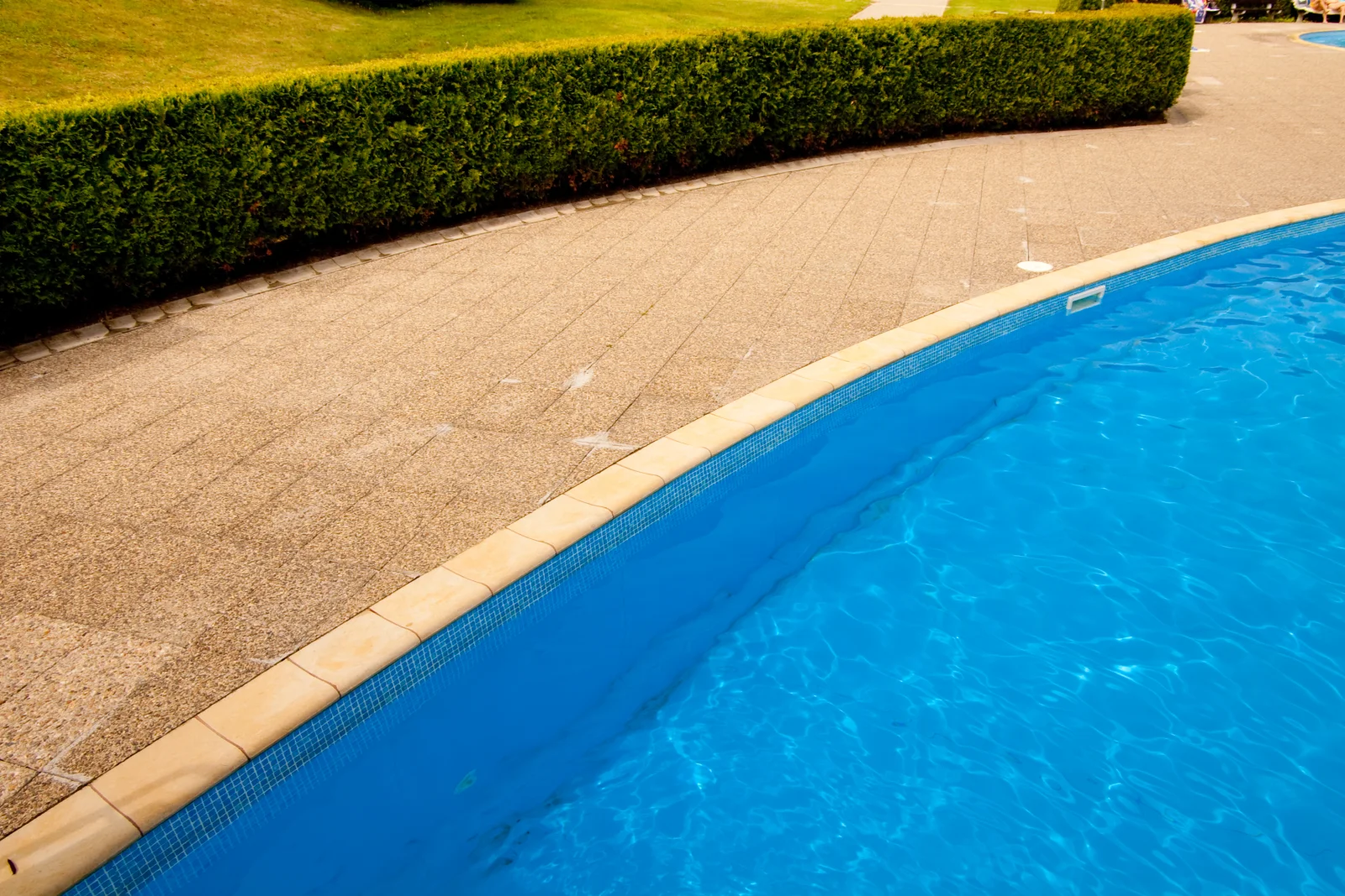 A finished Phoenix pool deck with a light-colored, slip-resistant textured coating around the pool.