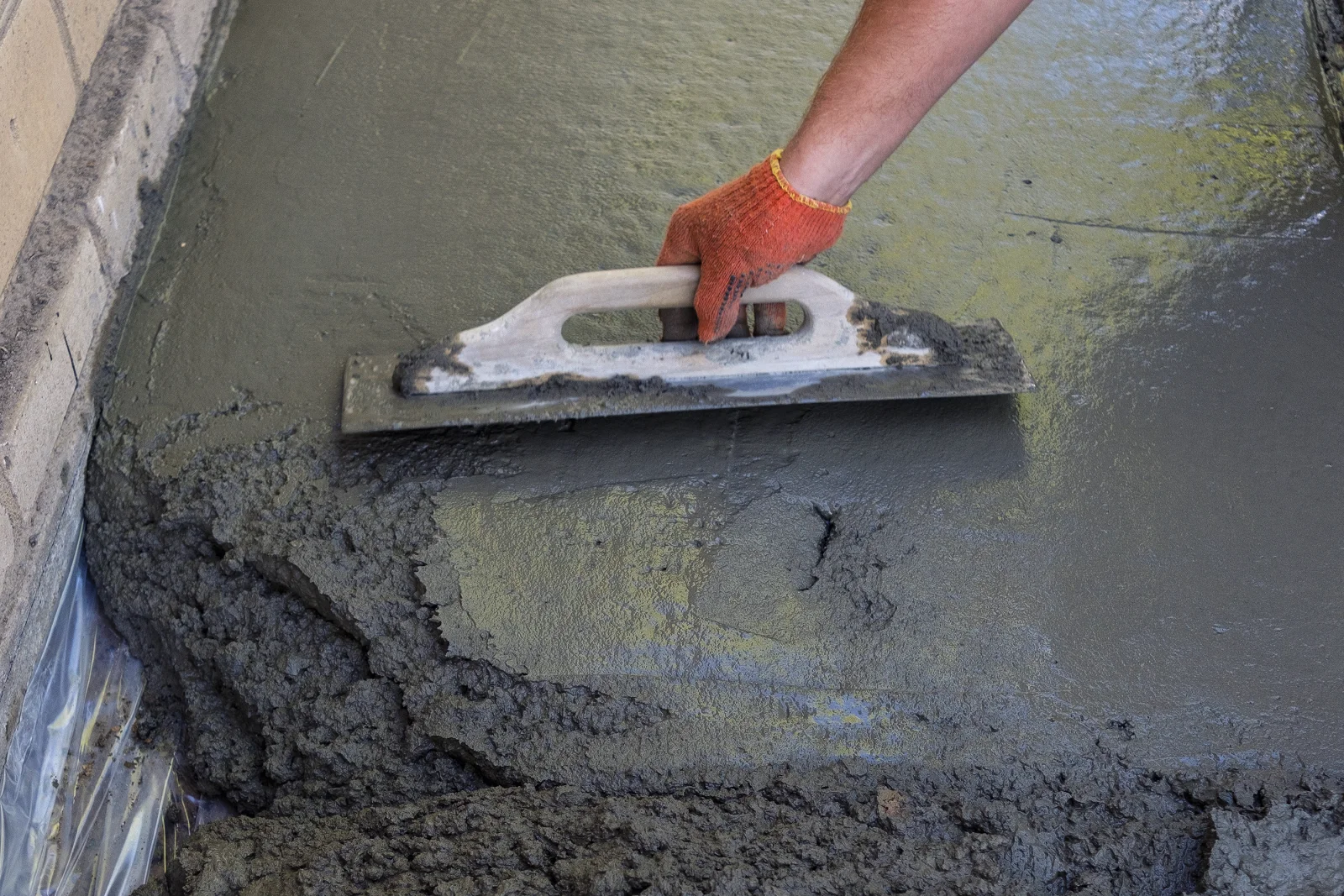 A pro troweling and smoothing a fresh concrete surface as part of pool deck surface prep in Phoenix.