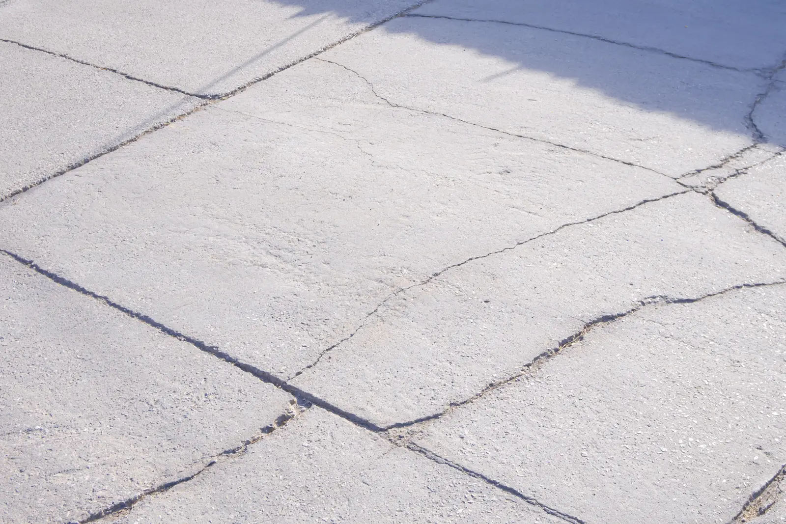 pool-deck-resurfacing-phoenix-cracked-spalling-concrete A cracked, spalling, sun-faded concrete pool deck in a Phoenix backyard baking in harsh afternoon light, showing the heat and UV damage that makes desert decks fail and need resurfacing.