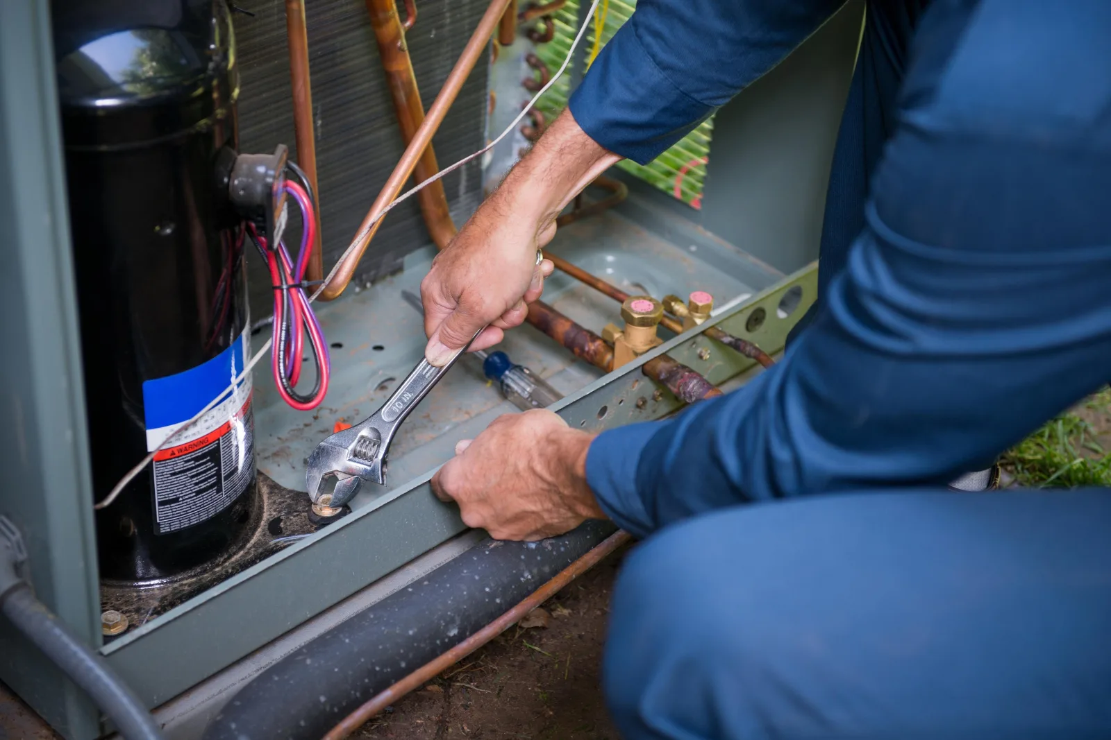 pool-heater-installation-phoenix-gas-electrical-connections Pool heater installation in Phoenix, Arizona — a technician connecting gas and electrical lines on outdoor heating equipment.