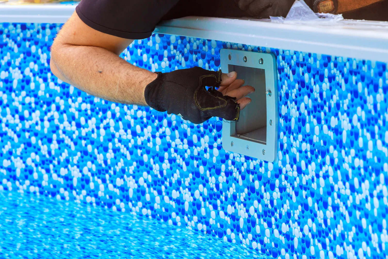 Pool light repair in Phoenix, Arizona — a gloved technician accessing a pool light niche and junction box on the pool wall.