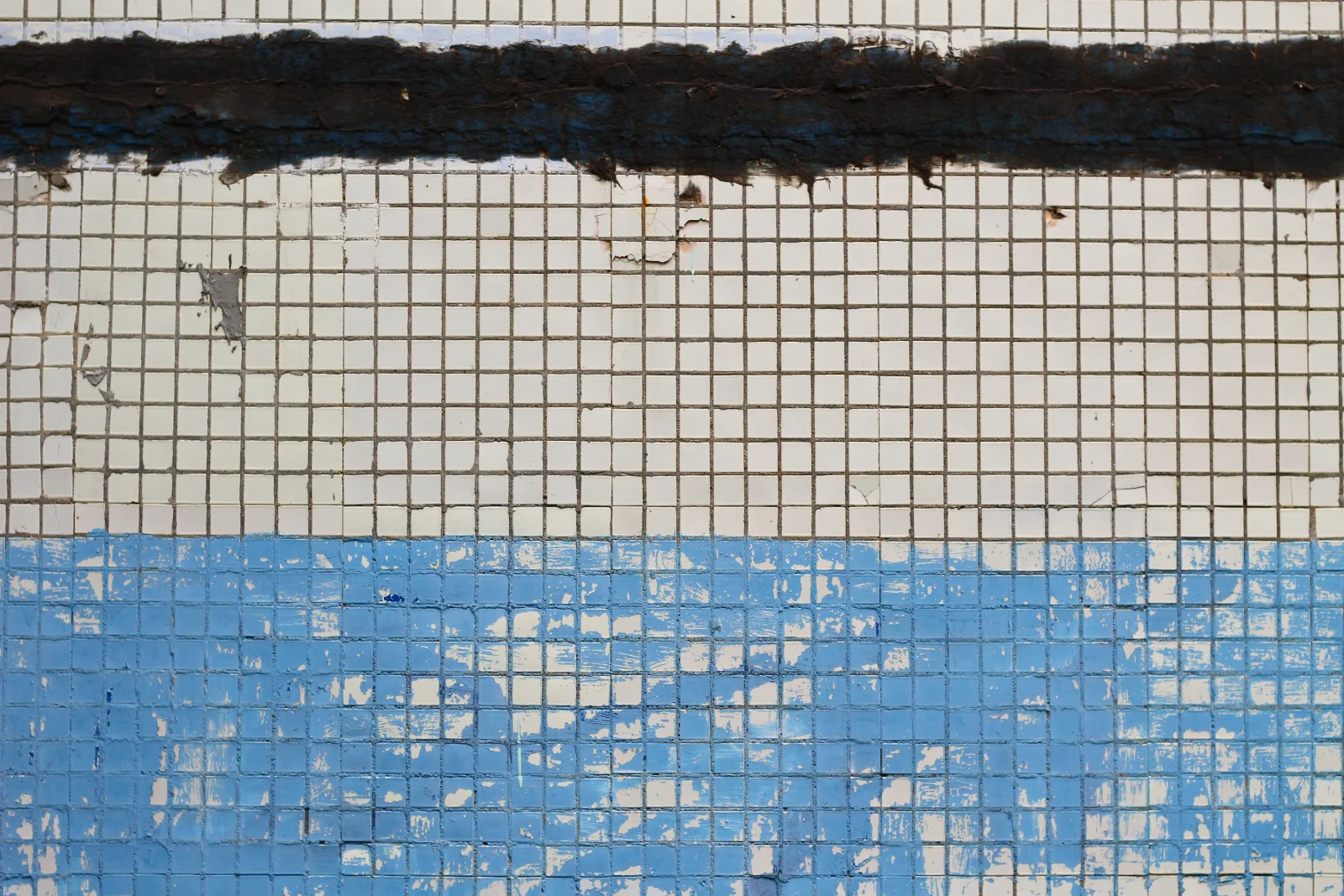 Close-up of white calcium scale buildup on waterline pool tile at a Phoenix home before professional cleaning.