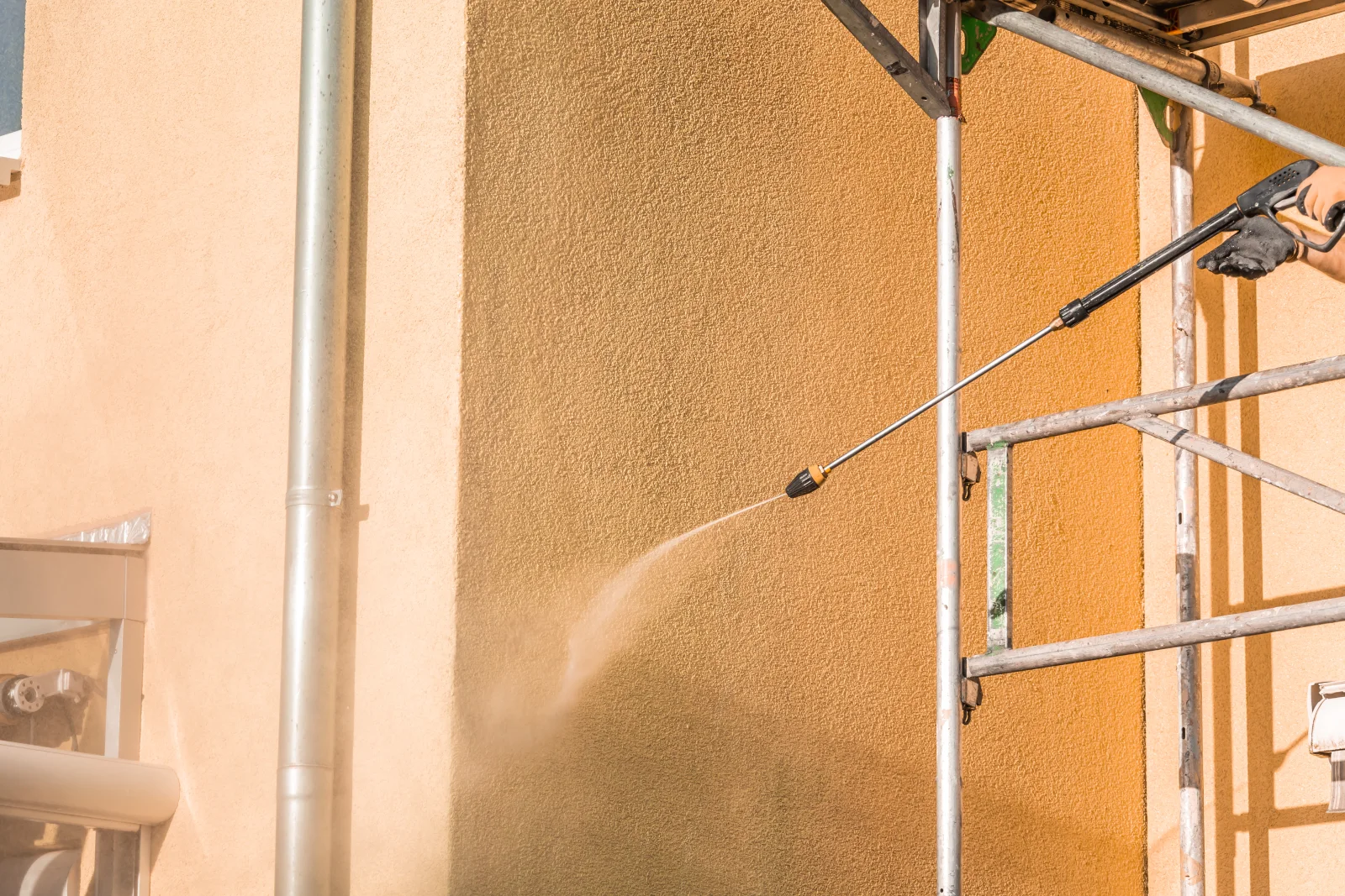A pressure-washing pro cleaning the exterior siding of a Phoenix home, the seasonal wash that keeps monsoon mud and hard water off the surface.