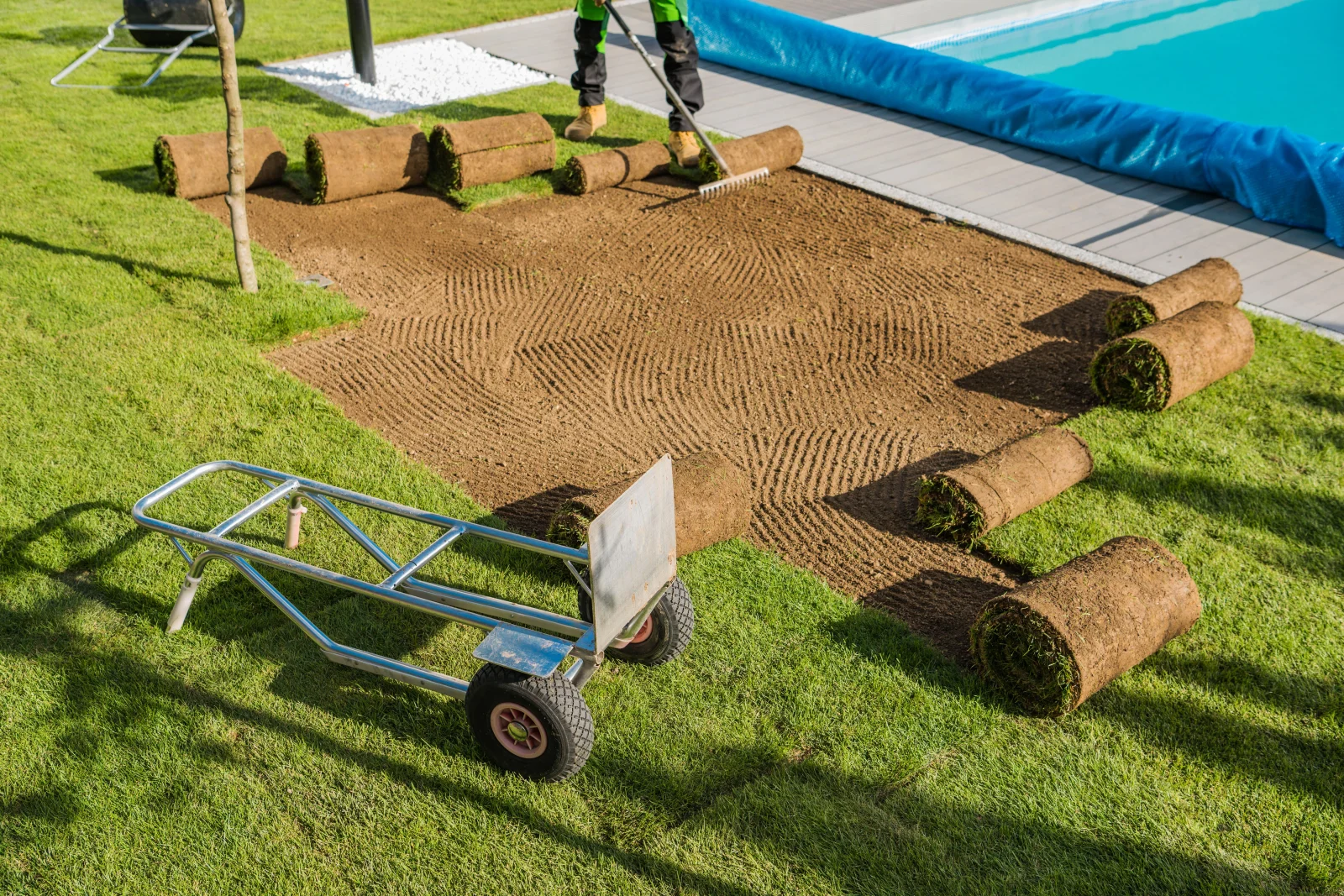 A landscaping crew grading and raking the compacted base in a Phoenix, Arizona backyard before putting green turf installation.