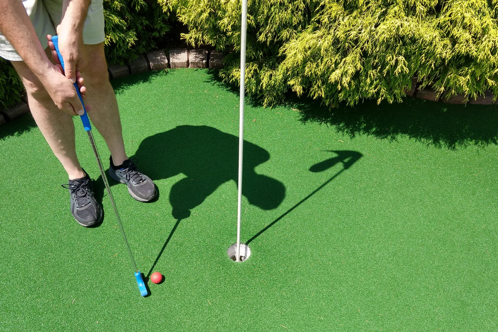 A finished backyard putting green in Phoenix, Arizona with a regulation cup, flag, and graded breaks, ready for play.