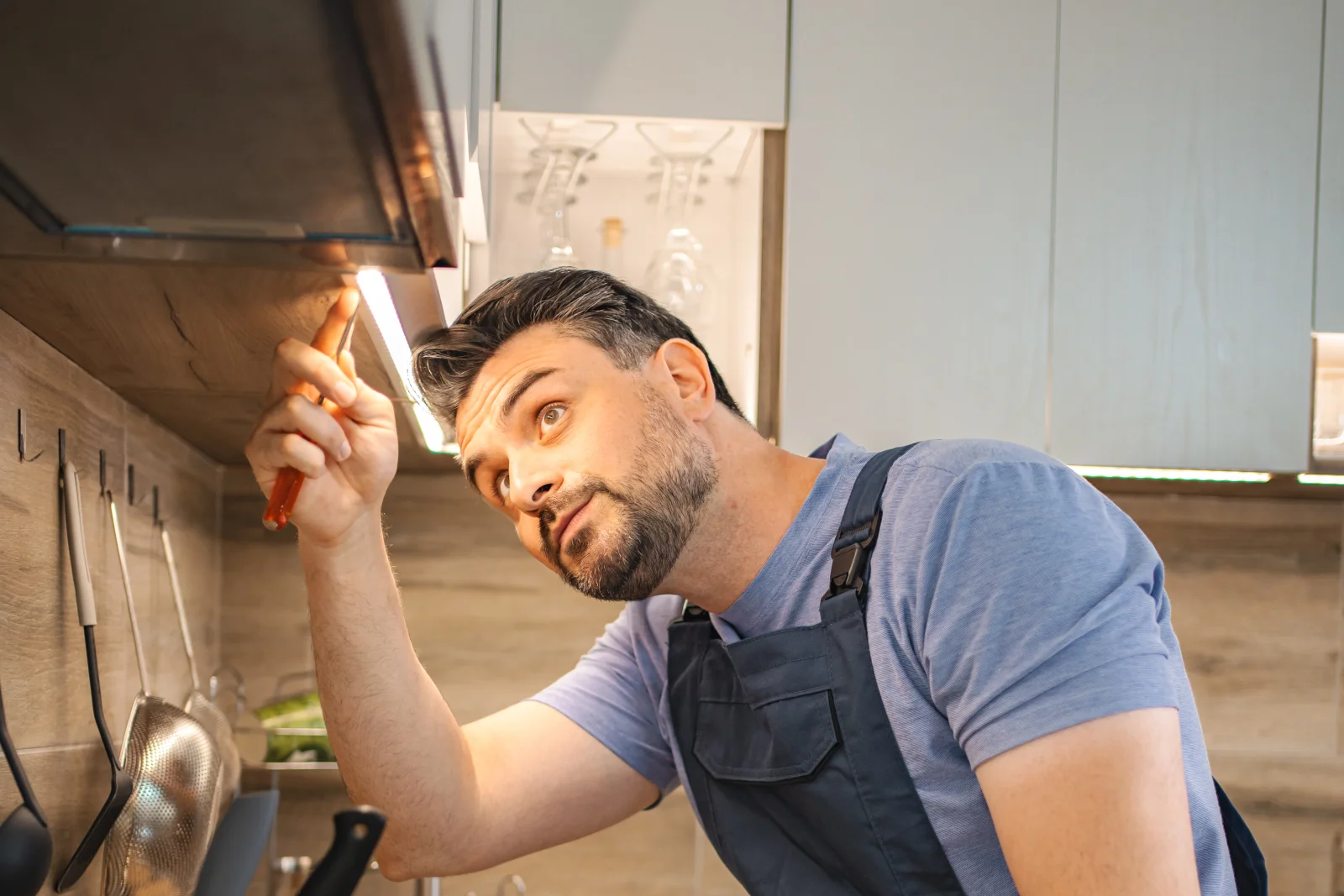 Range hood installation in Phoenix, Arizona — an installer checking the wiring and fit of a range hood in a residential kitchen.