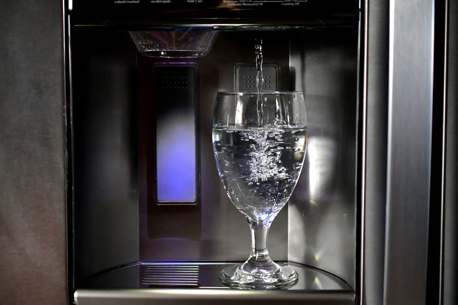 refrigerator-water-filter-replacement-phoenix-clean-water Refrigerator water filter replacement in Phoenix, Arizona, clear filtered water pouring from a stainless steel refrigerator dispenser into a glass.