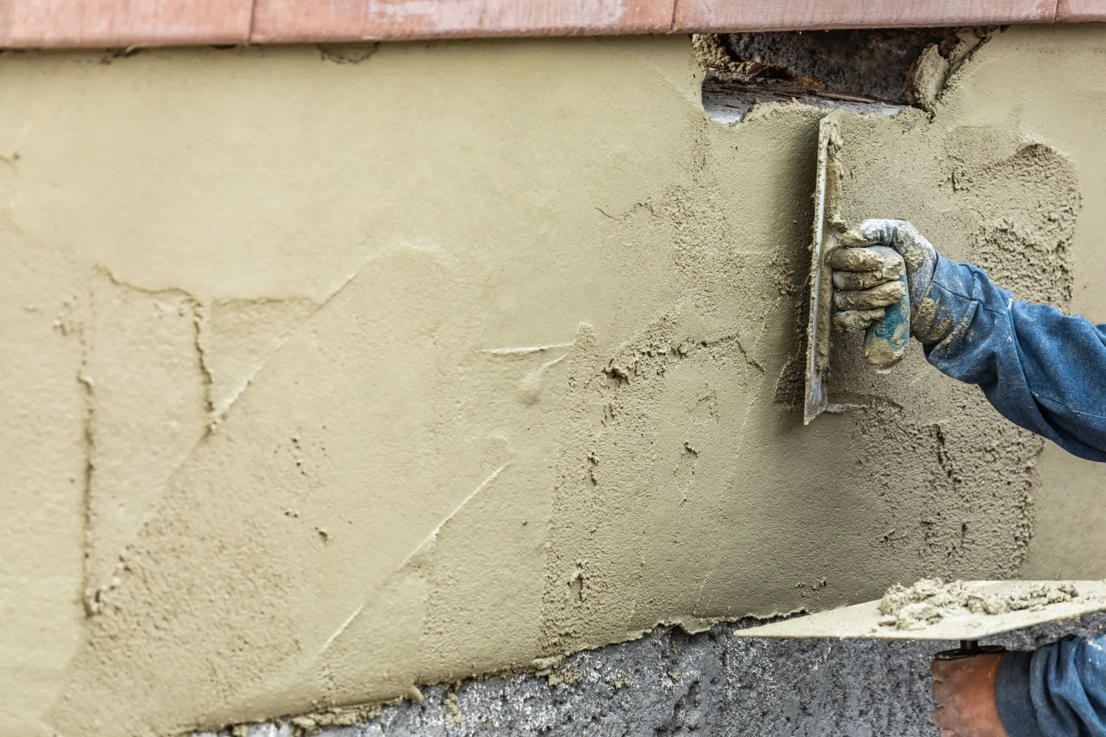 A close-up of a trowel finishing fresh stucco render on a Phoenix home's exterior wall, rated for intense desert sun and heat.