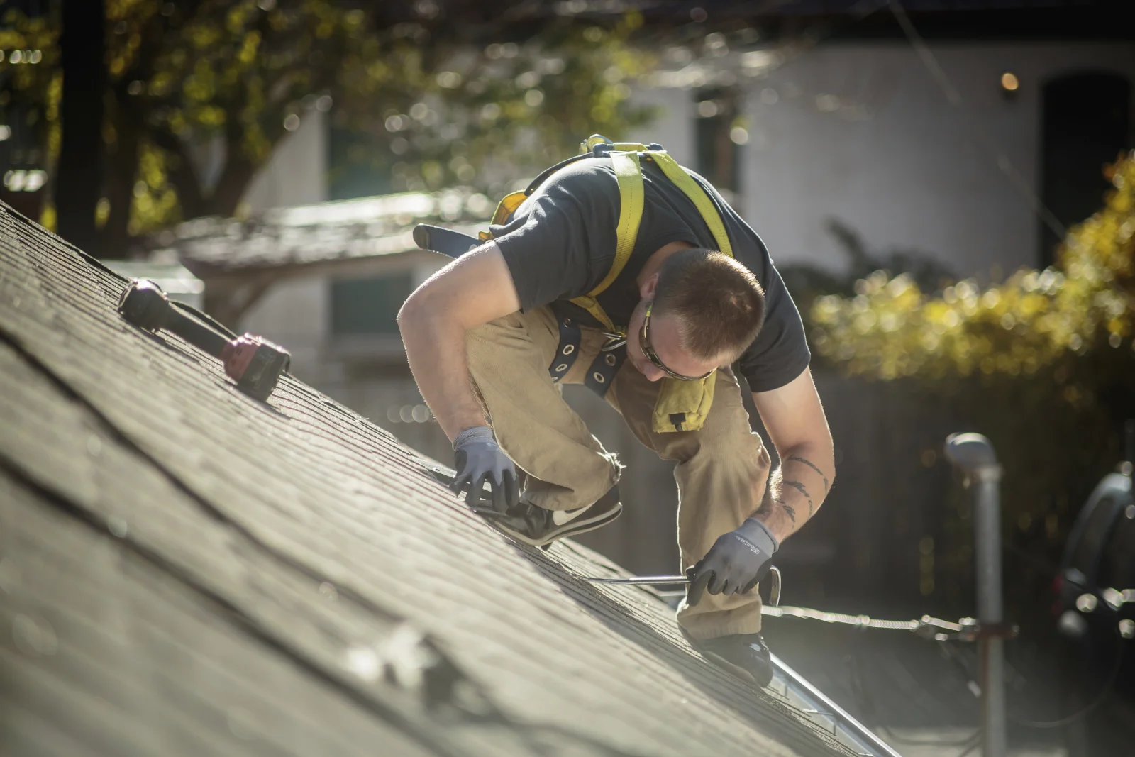reroofing-phoenix-safety-harness-residential-roof A roofer wearing a safety harness while working on a residential roof during a reroofing project in Phoenix, Arizona.