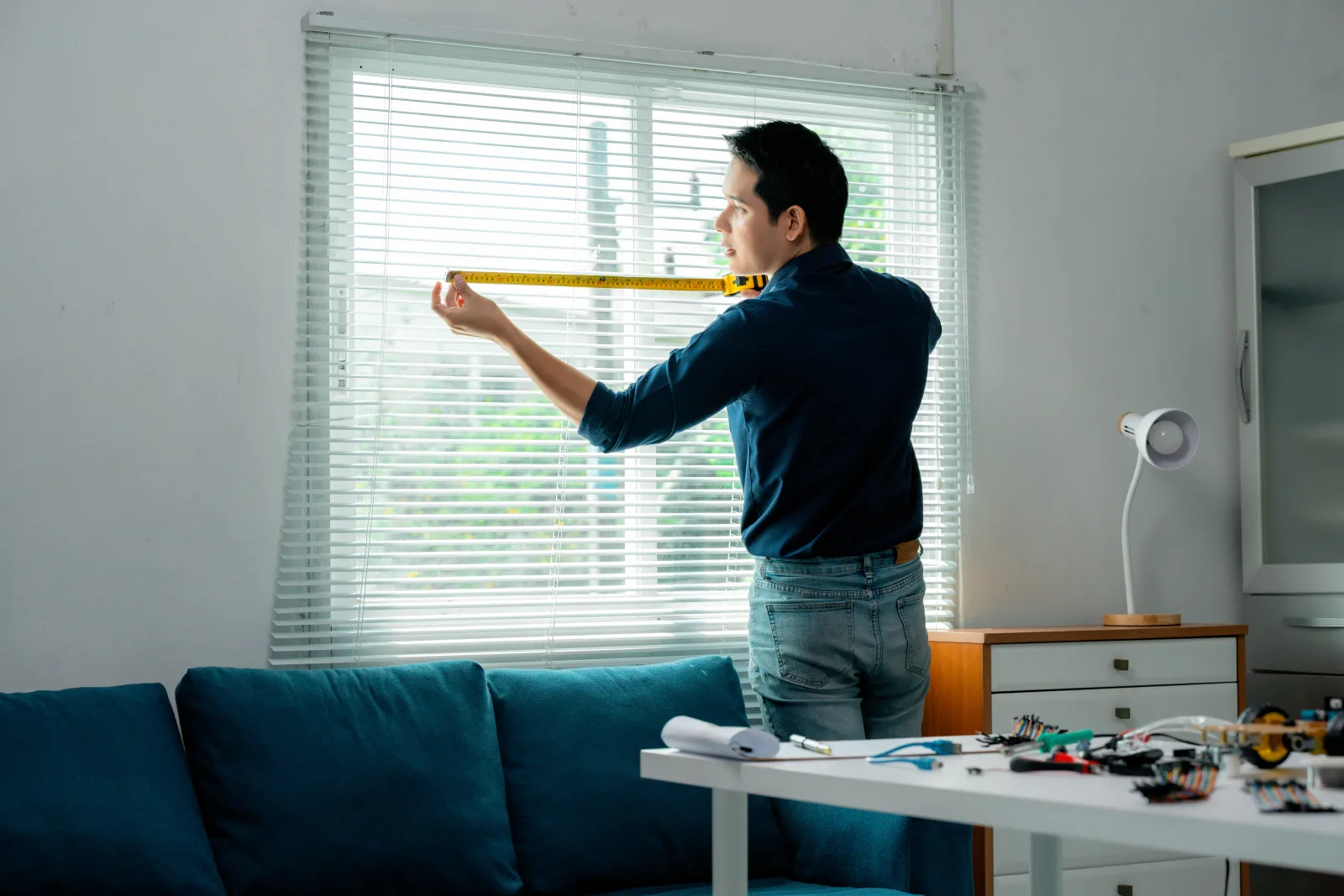 A pro measuring a window with a tape measure before ordering a custom roller shade.