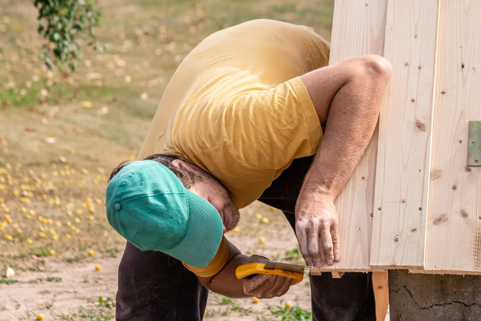 A carpenter nailing UV-treated wood siding onto the frame of a custom shed in Phoenix.