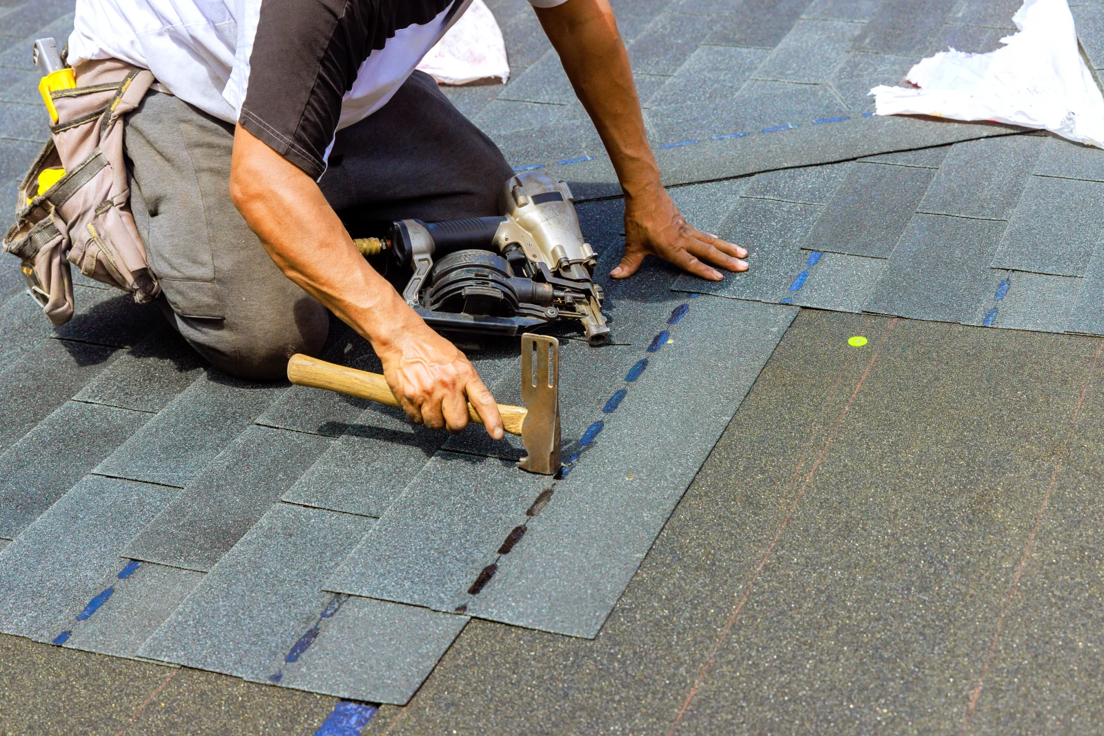 shingle-roof-installation-phoenix-hero Shingle roof installation in Phoenix - a roofer using a hammer and nail gun to install new asphalt shingles.