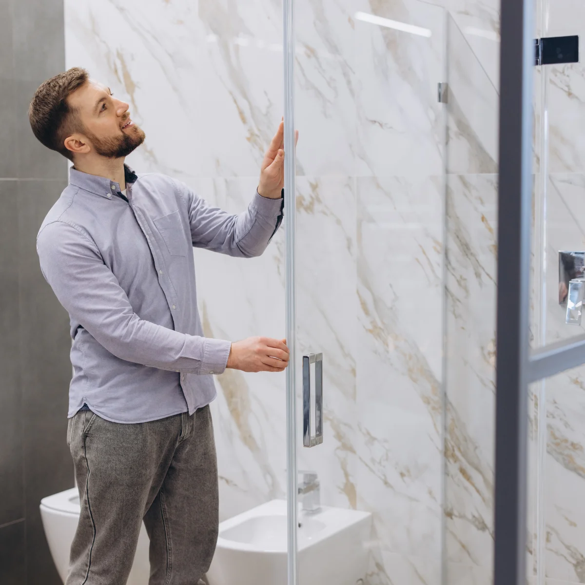 shower-door-installer-phoenix-frameless-glass Shower door installer in Phoenix, Arizona — a pro fitting a custom frameless glass shower door in a bright desert-style bathroom.