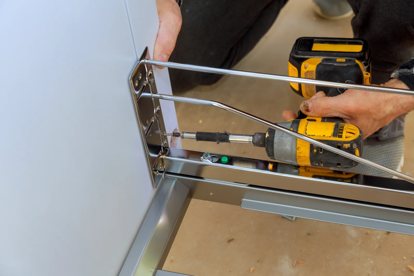 sliding-door-repair-phoenix-roller-track-hardware-repair Sliding door repair in Phoenix, Arizona — a close-up of a technician's hands using a power drill to repair roller hardware on a sliding door track.