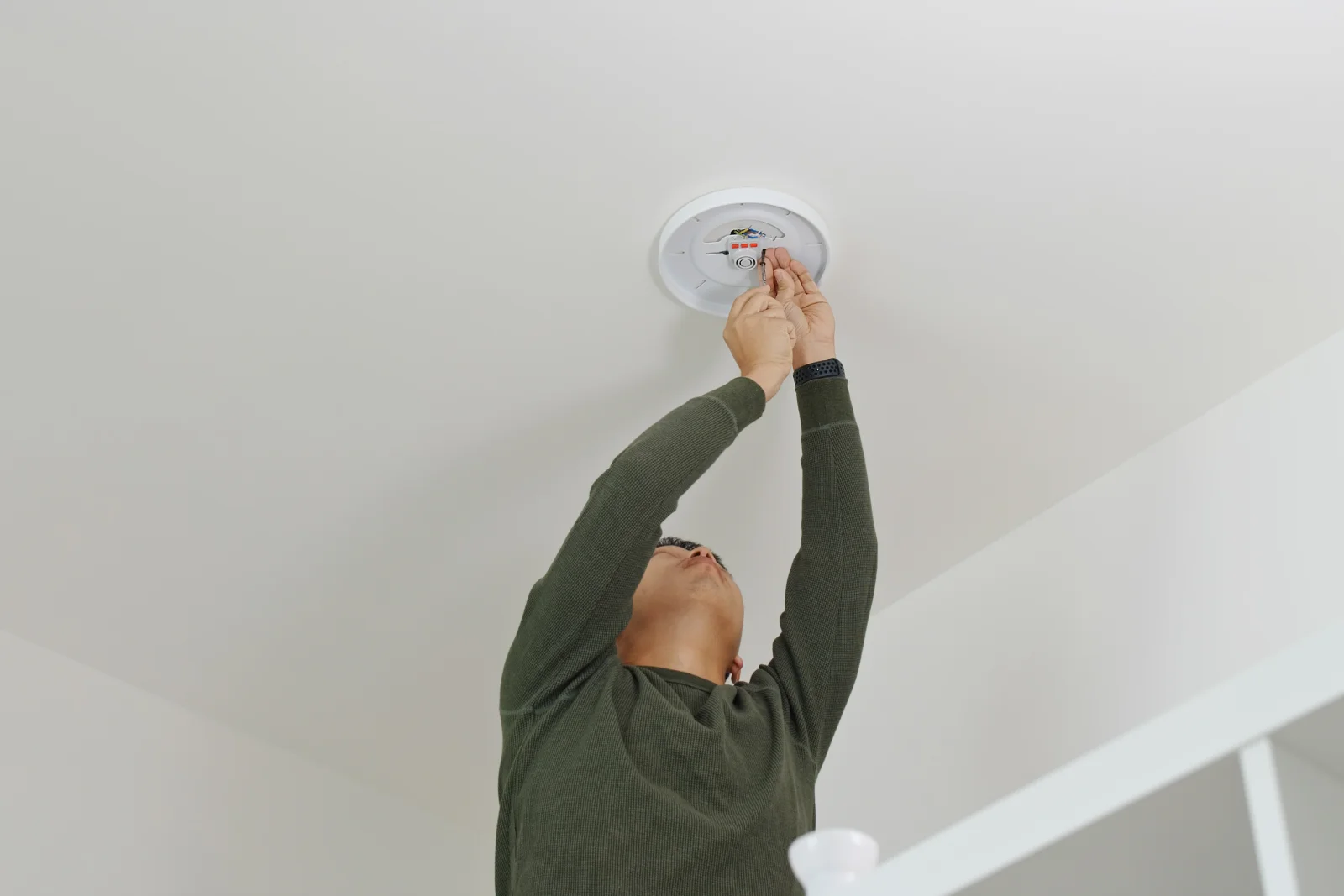 A newly installed smoke detector mounted on a vaulted ceiling in a Phoenix home.