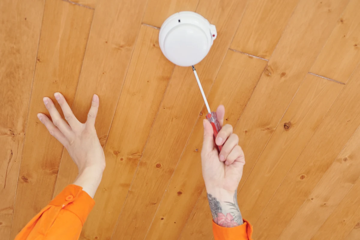 smoke-detector-repair-phoenix-detector-repair Smoke detector repair in Phoenix, Arizona — a licensed electrician repairing a ceiling-mounted smoke detector in a home.