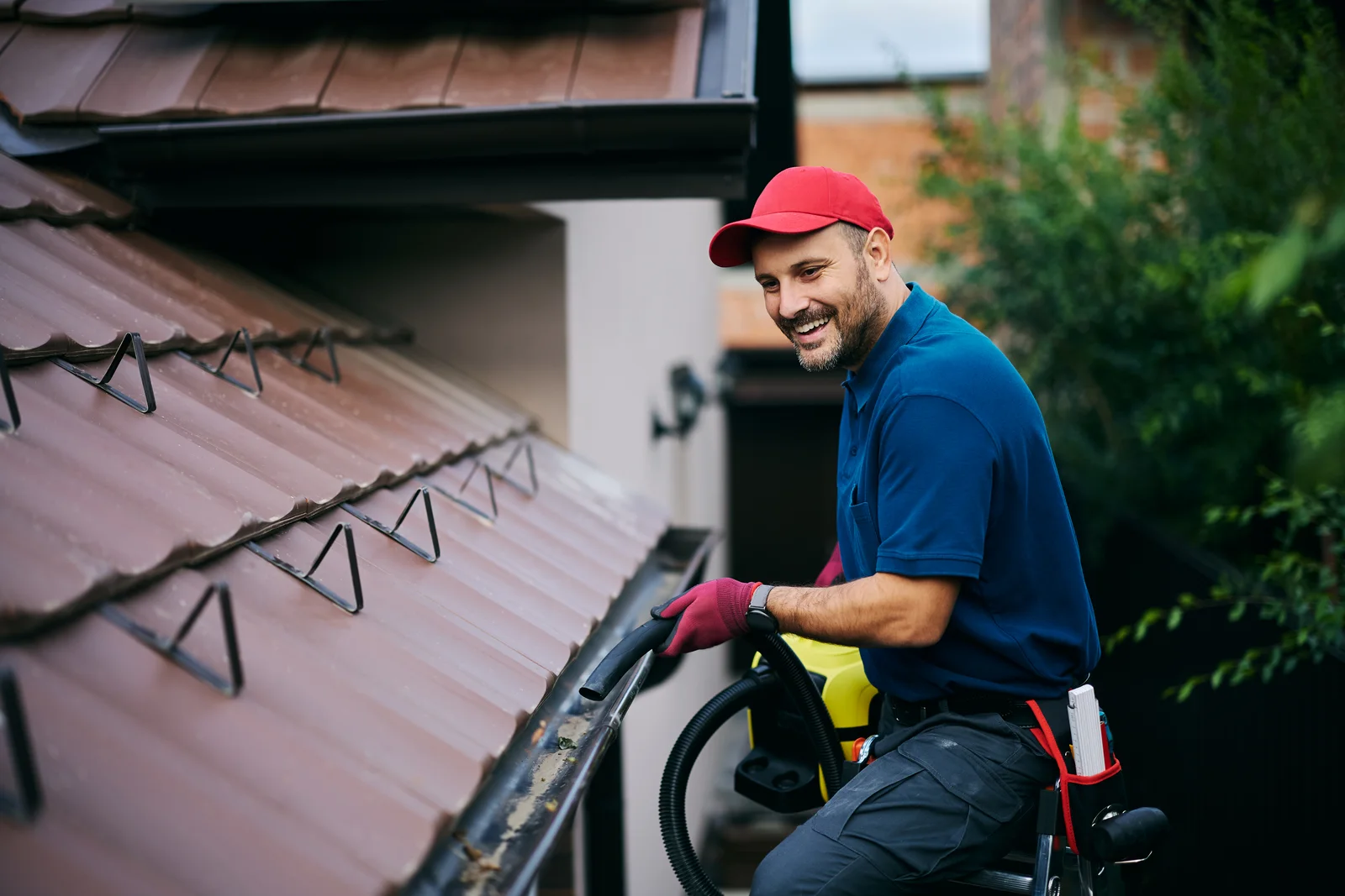 A soft-wash pro clearing debris from a roof edge and gutter as part of a Phoenix home exterior cleaning.