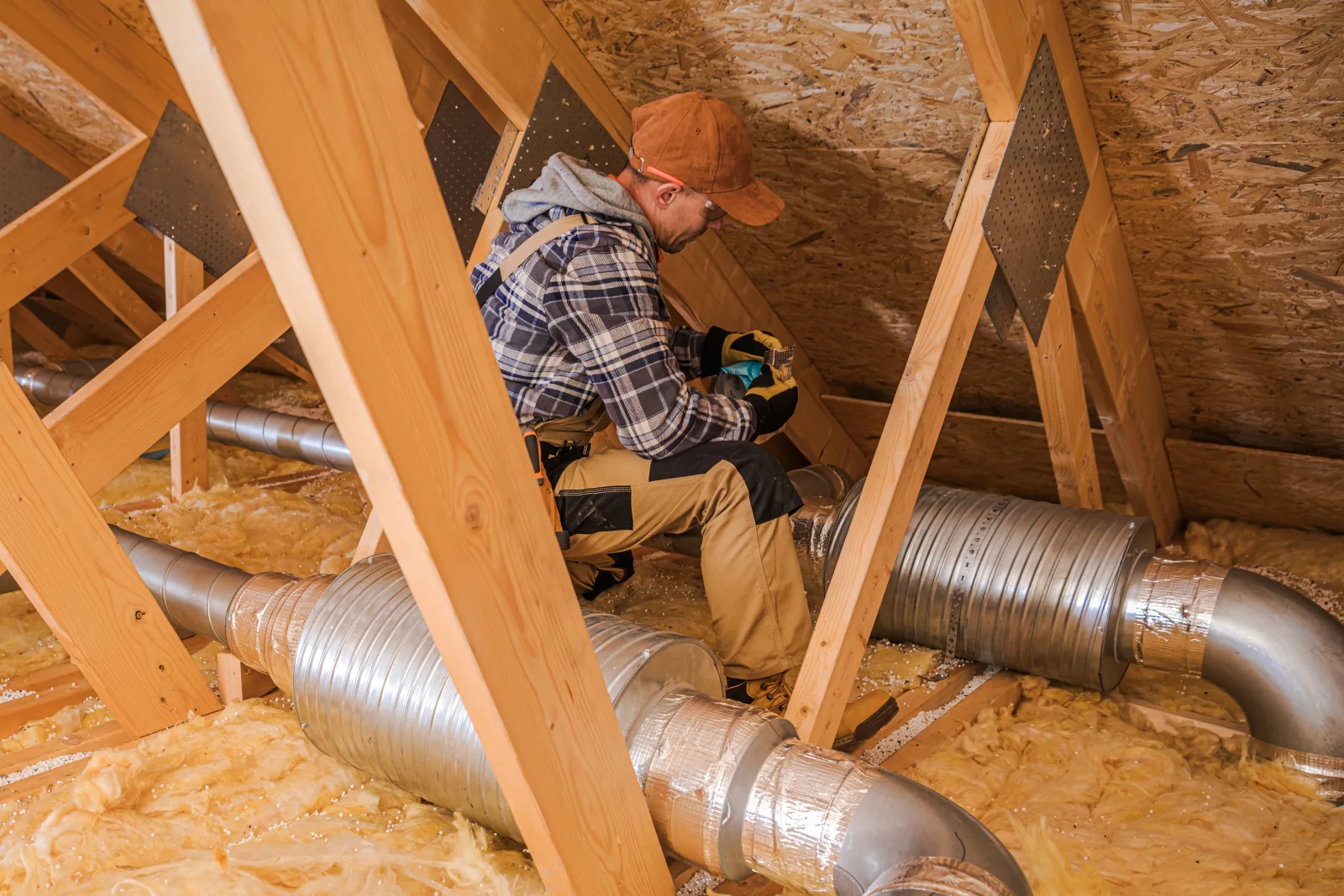 solar-tube-installation-phoenix-attic-tube-routing Solar tube installation in Phoenix, Arizona — an installer routing tubing through the attic trusses and insulation on the way to the ceiling opening.