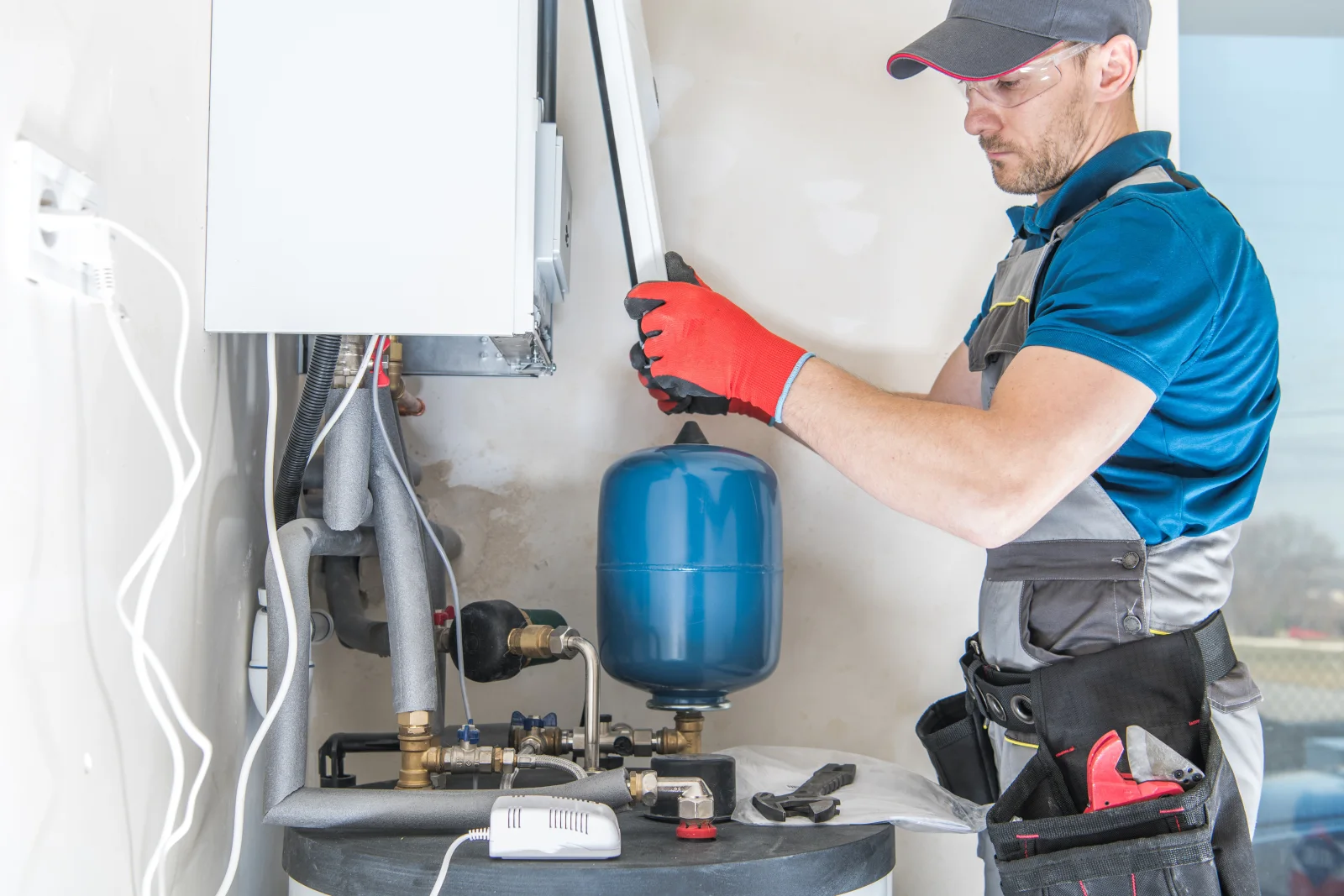 solar-water-heater-service-phoenix-controller-diagnostics A Phoenix plumber checking a solar water heater's controller and gauges in a home utility closet to diagnose why the system isn't delivering enough hot water.