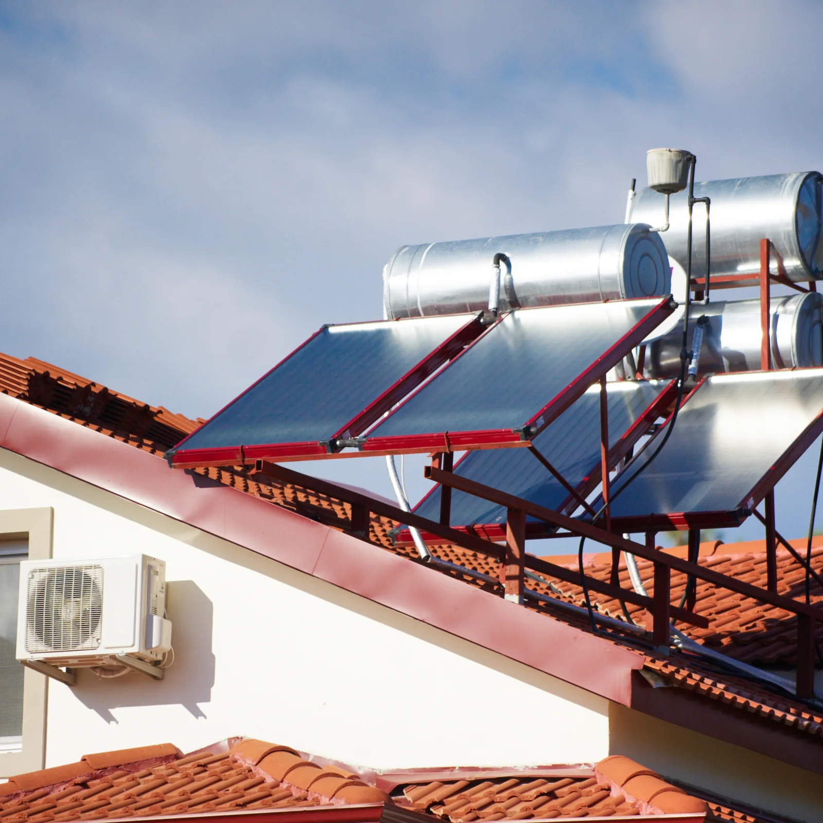 solar-water-heater-service-phoenix-rooftop-technician Solar water heater service in Phoenix, Arizona — a technician in uniform inspecting rooftop solar thermal collector panels on a home under a bright desert sky.