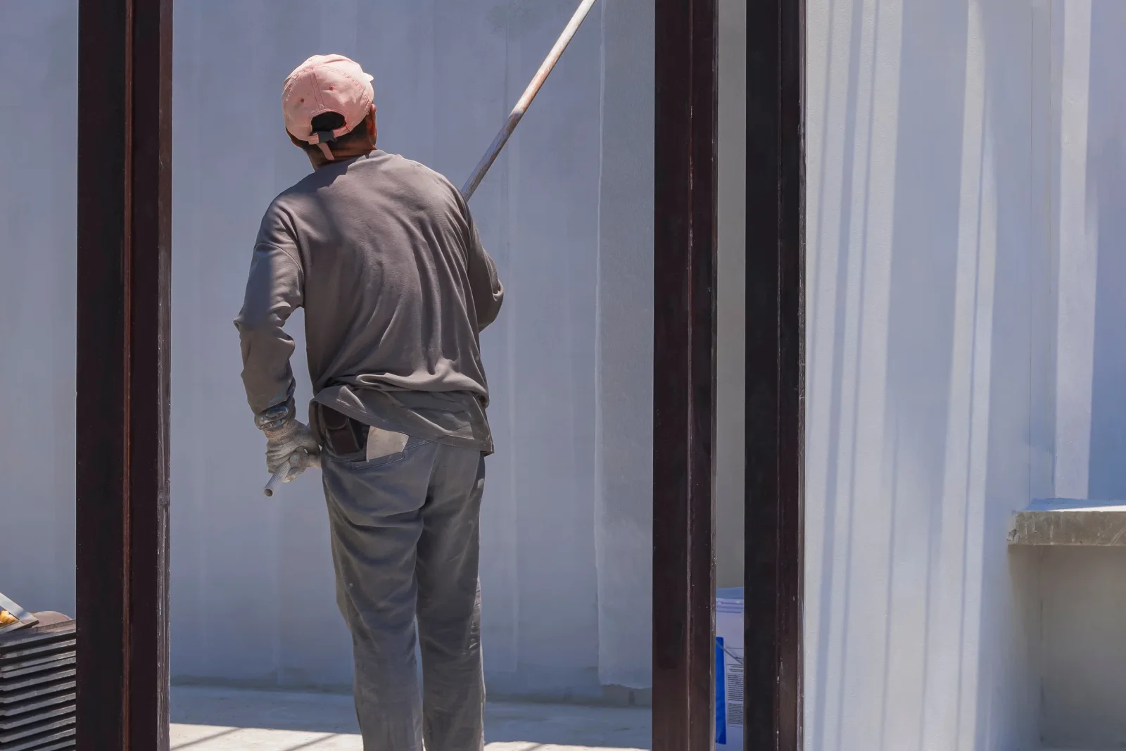 stucco-painting-phoenix-masonry-coating-roller-application A painter using an extension roller to apply a masonry-grade coating to exterior stucco on a Phoenix, Arizona building.