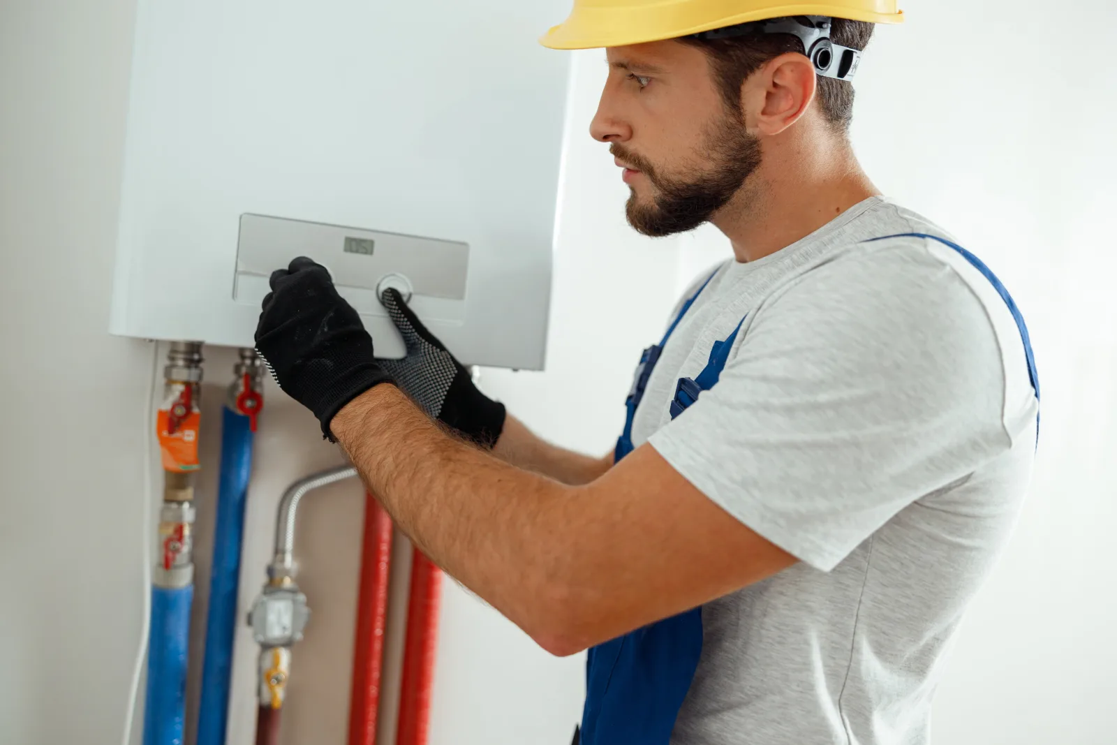 tankless-water-heater-phoenix-control-panel-setup A technician in a hard hat setting up the control panel and gas lines on a tankless water heater in a Phoenix, Arizona home.
