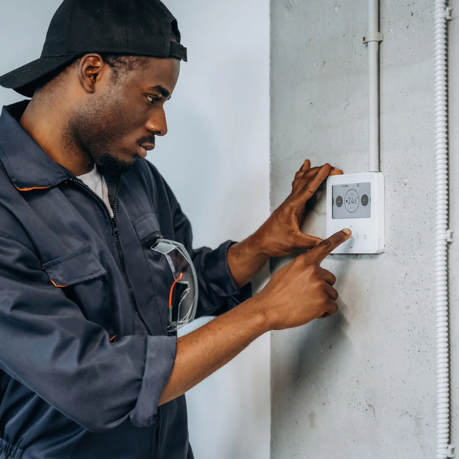 thermostat-repair-phoenix-hvac-technician Thermostat repair in Phoenix, Arizona — a uniformed HVAC technician diagnosing a wall-mounted thermostat's wiring.
