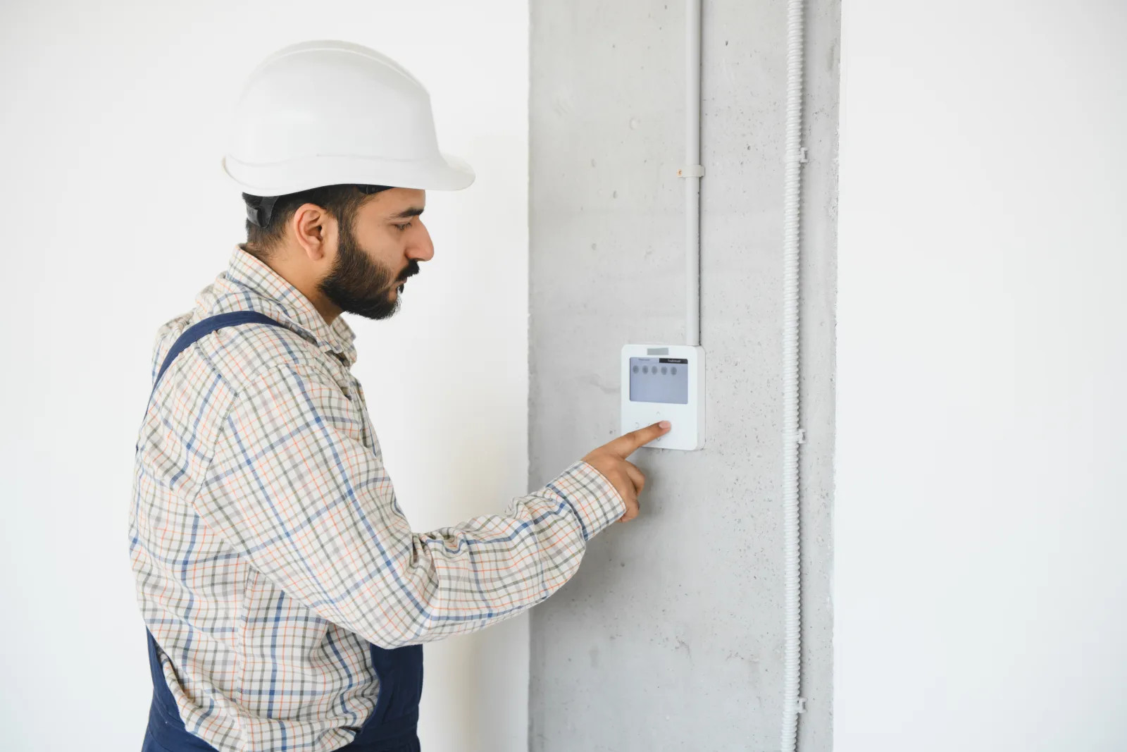 thermostat-repair-phoenix-smart-thermostat-install An HVAC technician installing and pairing a smart thermostat on a wall inside a Phoenix home, confirming C-wire compatibility before finishing the job.