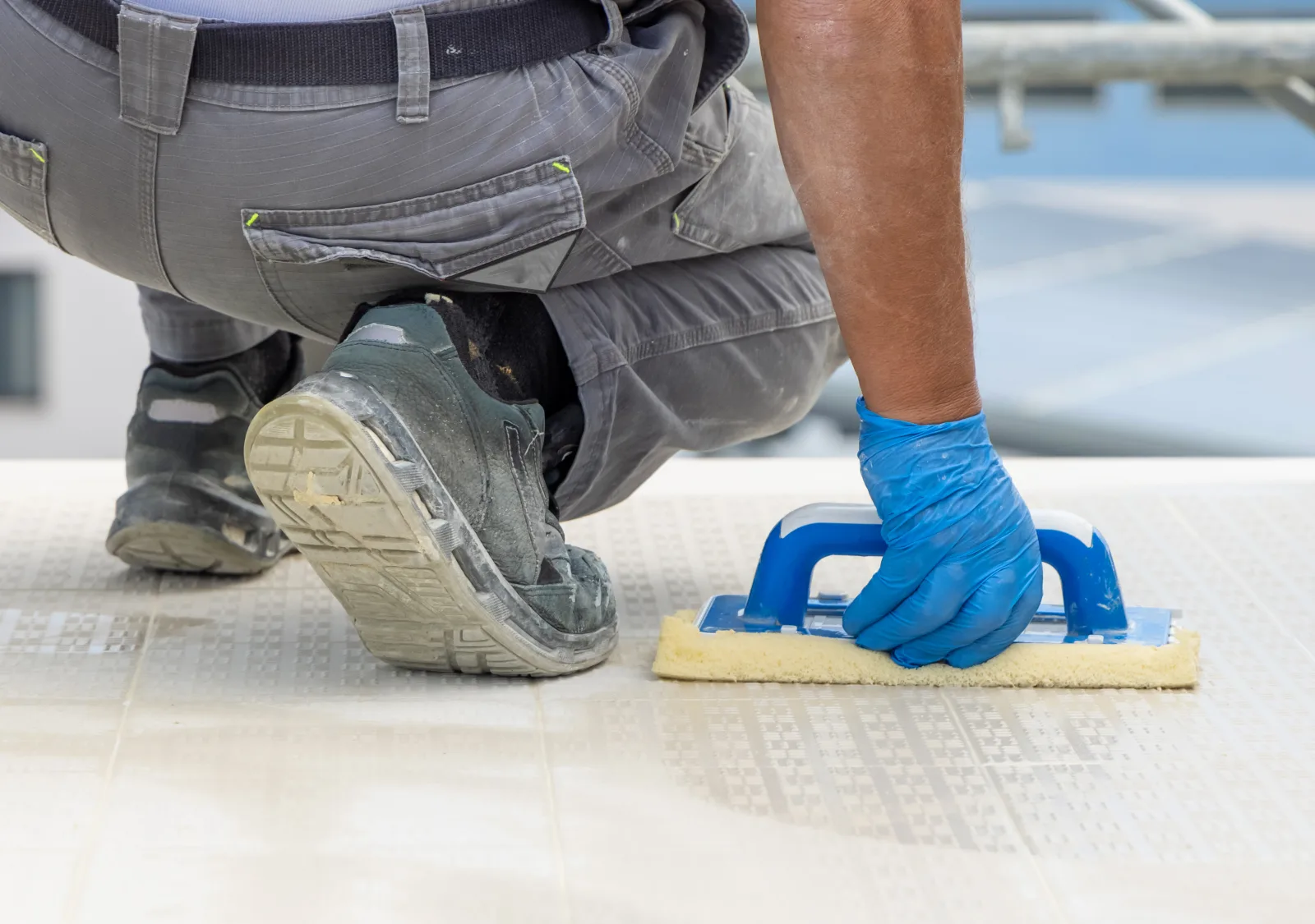 tile-and-grout-cleaning-phoenix-az-hard-water-scale-removal Tile and grout cleaning in Phoenix, Arizona — a technician's gloved hand using a grout float and cleaning pad to remove hard-water scale from tile.