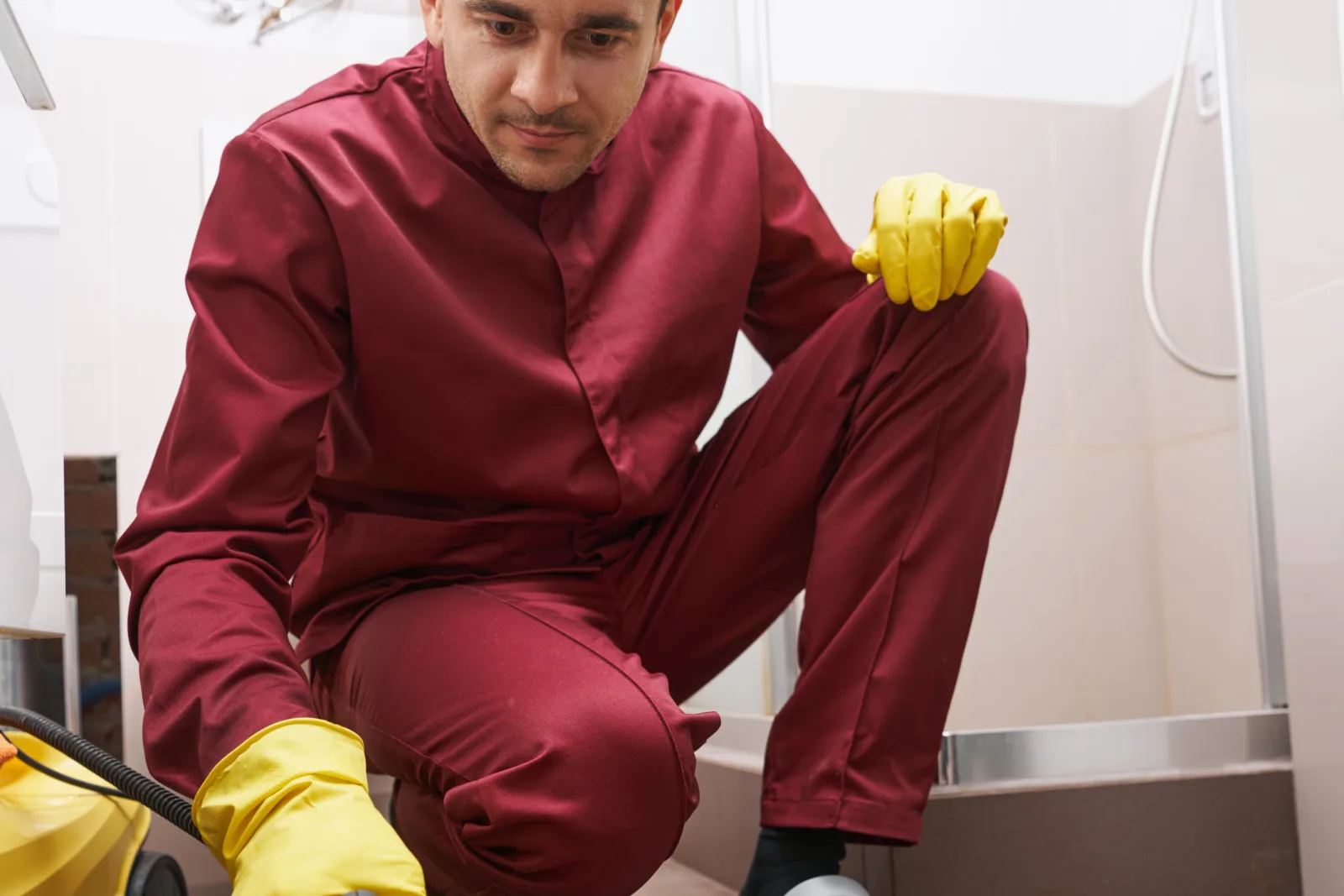 tile-and-grout-cleaning-phoenix-az-technician-steam-cleaning-bathroom-floor Tile and grout cleaning in Phoenix, Arizona — a technician in a work uniform using a steam cleaner on tile floor grout lines in a bathroom.