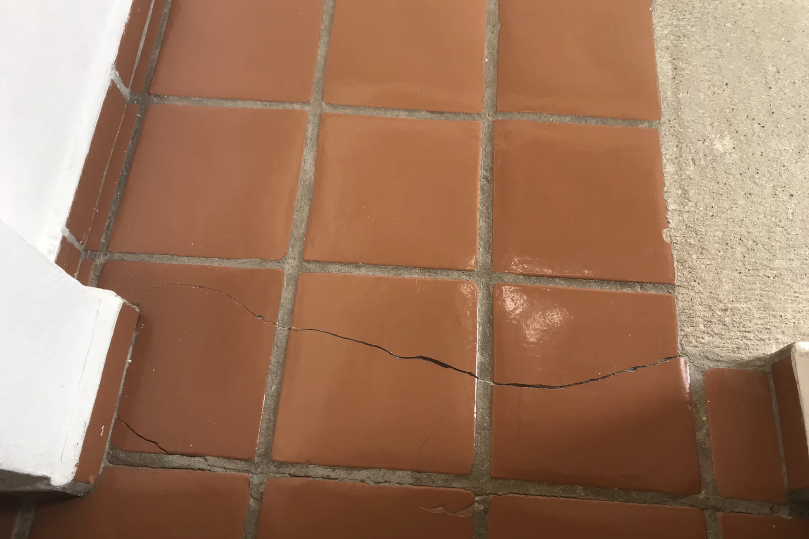 A cracked terracotta floor tile in a Phoenix home, showing the kind of slab-movement damage a tile repair pro fixes.