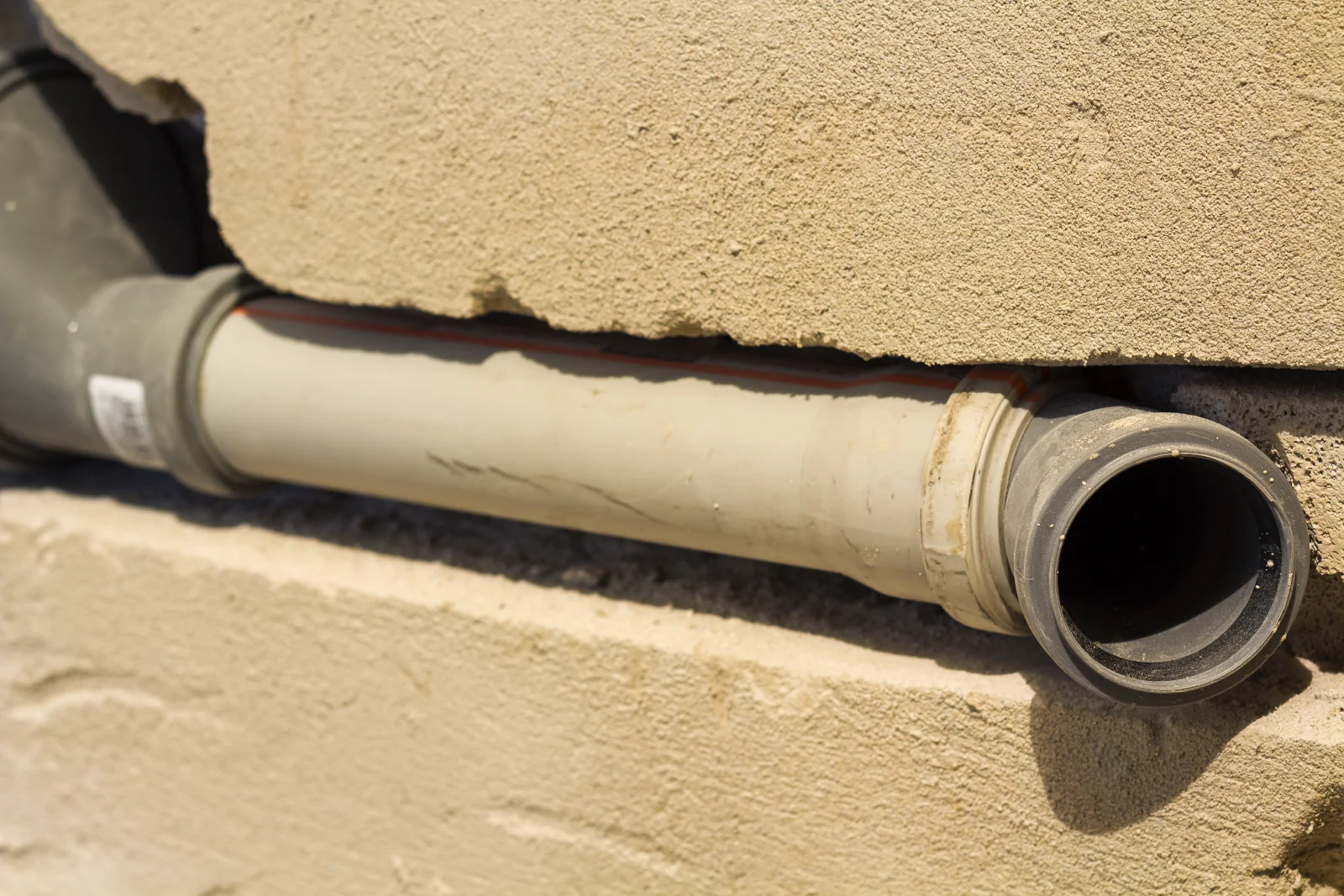 A deteriorated clay sewer pipe exposed at a Phoenix home's foundation, the kind of aging line trenchless sewer repair replaces.