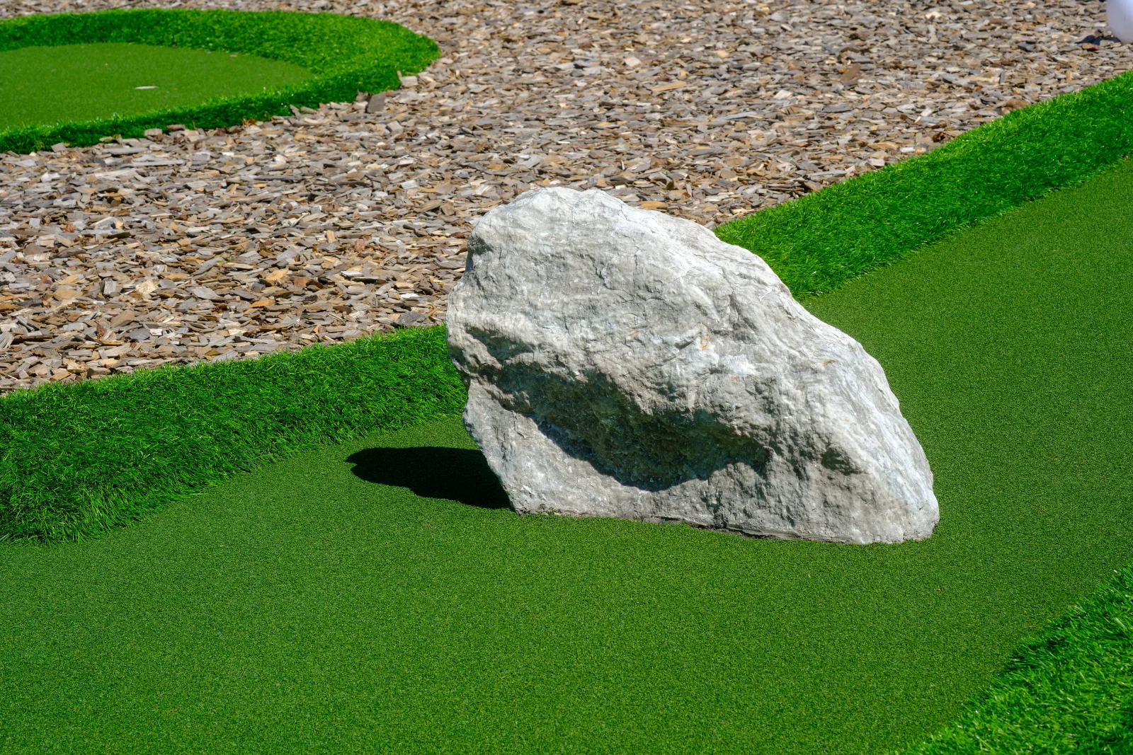 turf-installation-phoenix-desert-rock-border-landscaping Artificial turf edged against decomposed granite and a boulder accent in a Phoenix-style desert landscaping design.