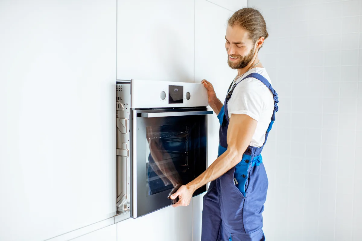 wall-oven-installation-phoenix-installer-fitting-oven Wall oven installation in Phoenix, Arizona — an appliance installer fitting a built-in wall oven into a kitchen cabinet cutout.