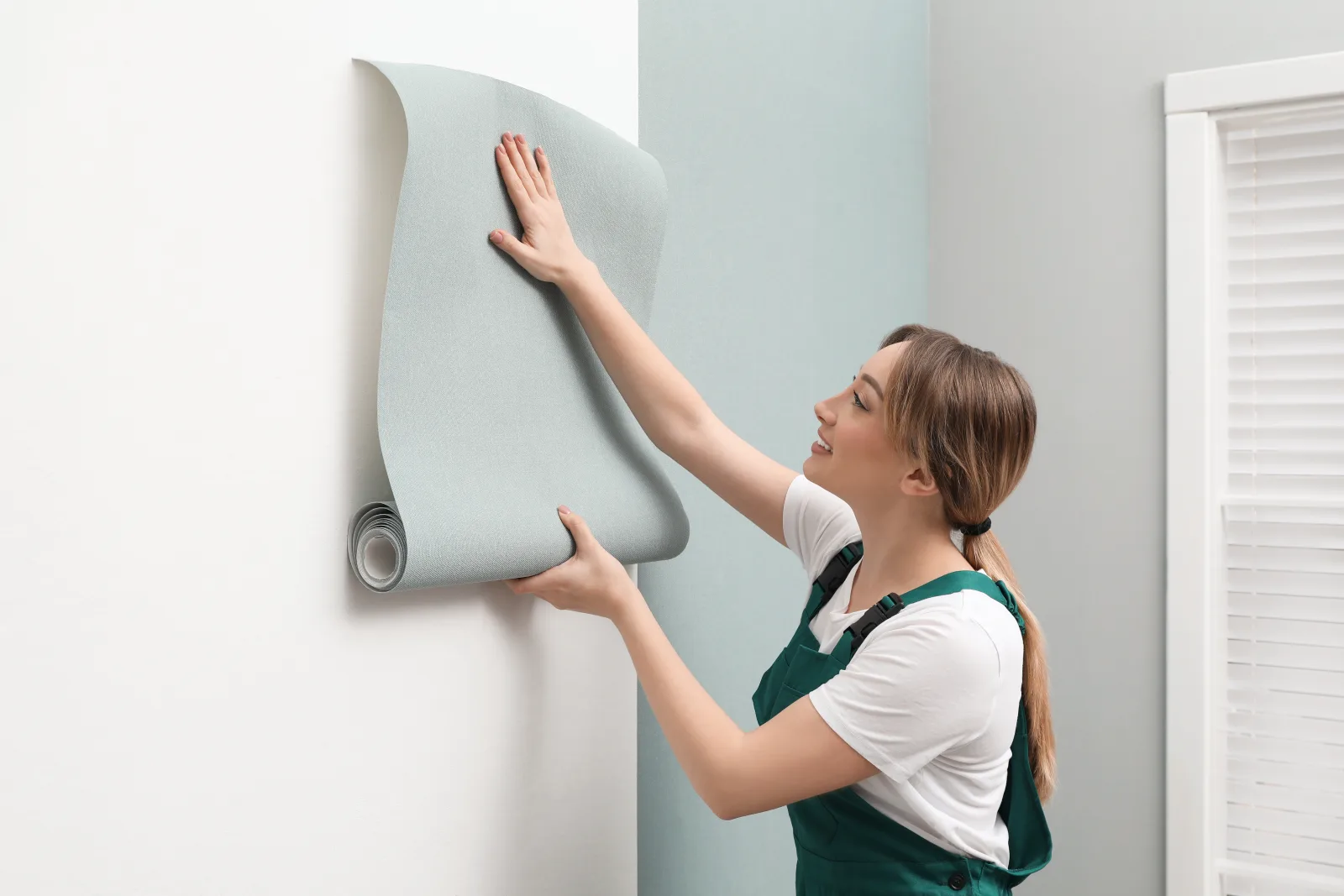 wallpaper-installation-phoenix-installer-hanging-wallpaper Wallpaper installation in Phoenix, Arizona — an installer smoothing a fresh strip of wallpaper onto a wall in a bright, modern room.