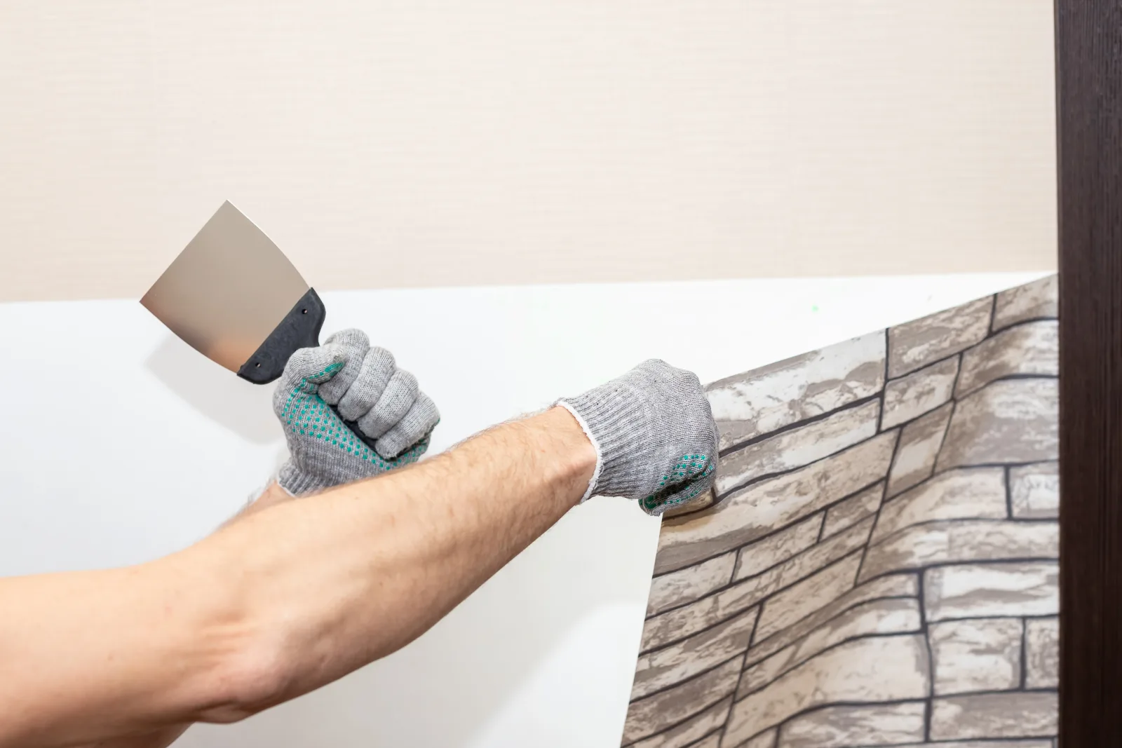 wallpaper-installation-phoenix-seam-smoothing-tool Wallpaper installation in Phoenix, Arizona — a close-up of a hand using a smoothing tool to press a wallpaper seam flat against the wall.