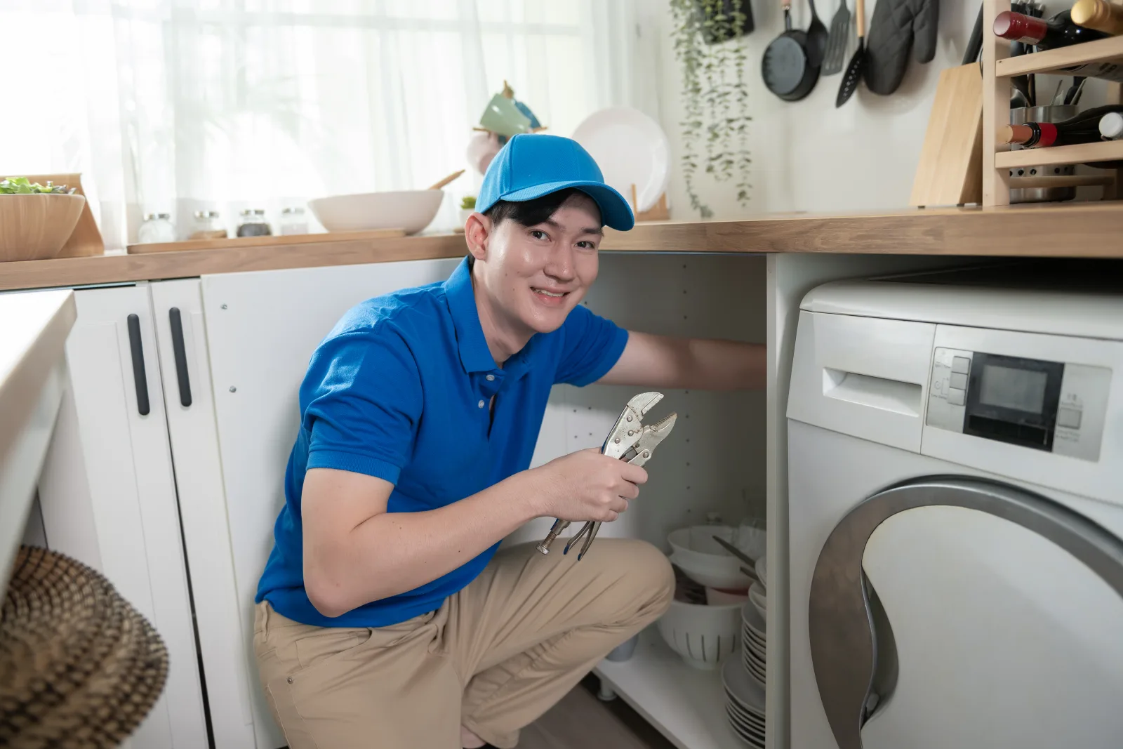 An appliance technician pulling a washing machine away from a Phoenix laundry room wall to inspect the drain pump and hose connections before quoting a repair.