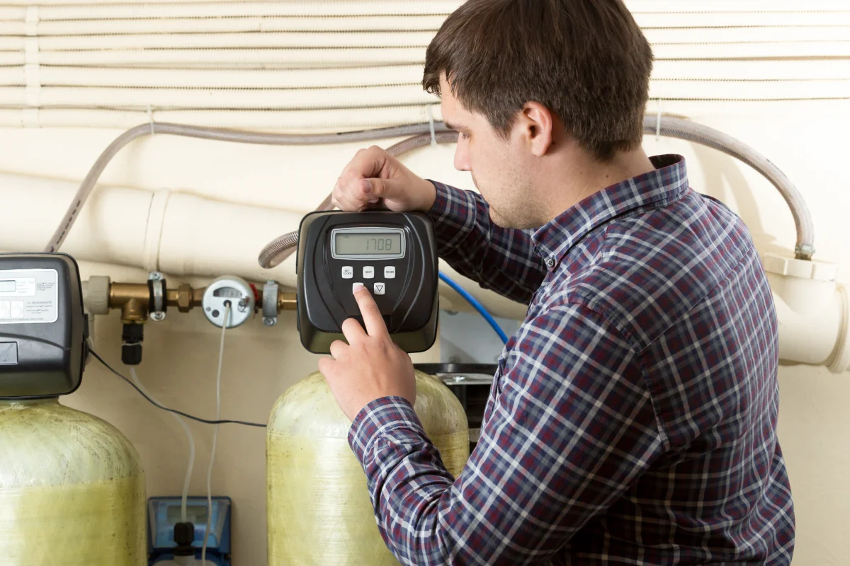 water-softener-installation-phoenix-control-head-programming Water softener installation in Phoenix, Arizona — a technician in a plaid shirt programming the digital control head of a whole-house water softener system.