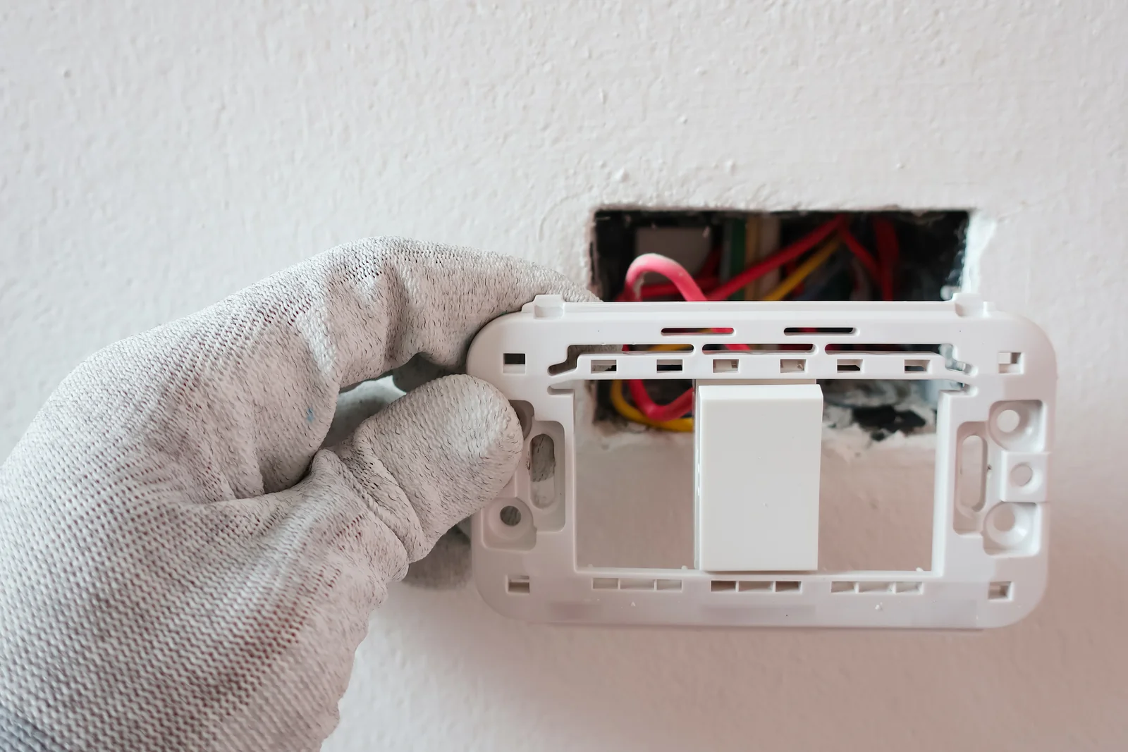 whole-house-fan-installation-phoenix-wall-control-wiring Whole house fan installation in Phoenix, Arizona — an electrician wiring a wall-mounted control switch for a whole house fan system.