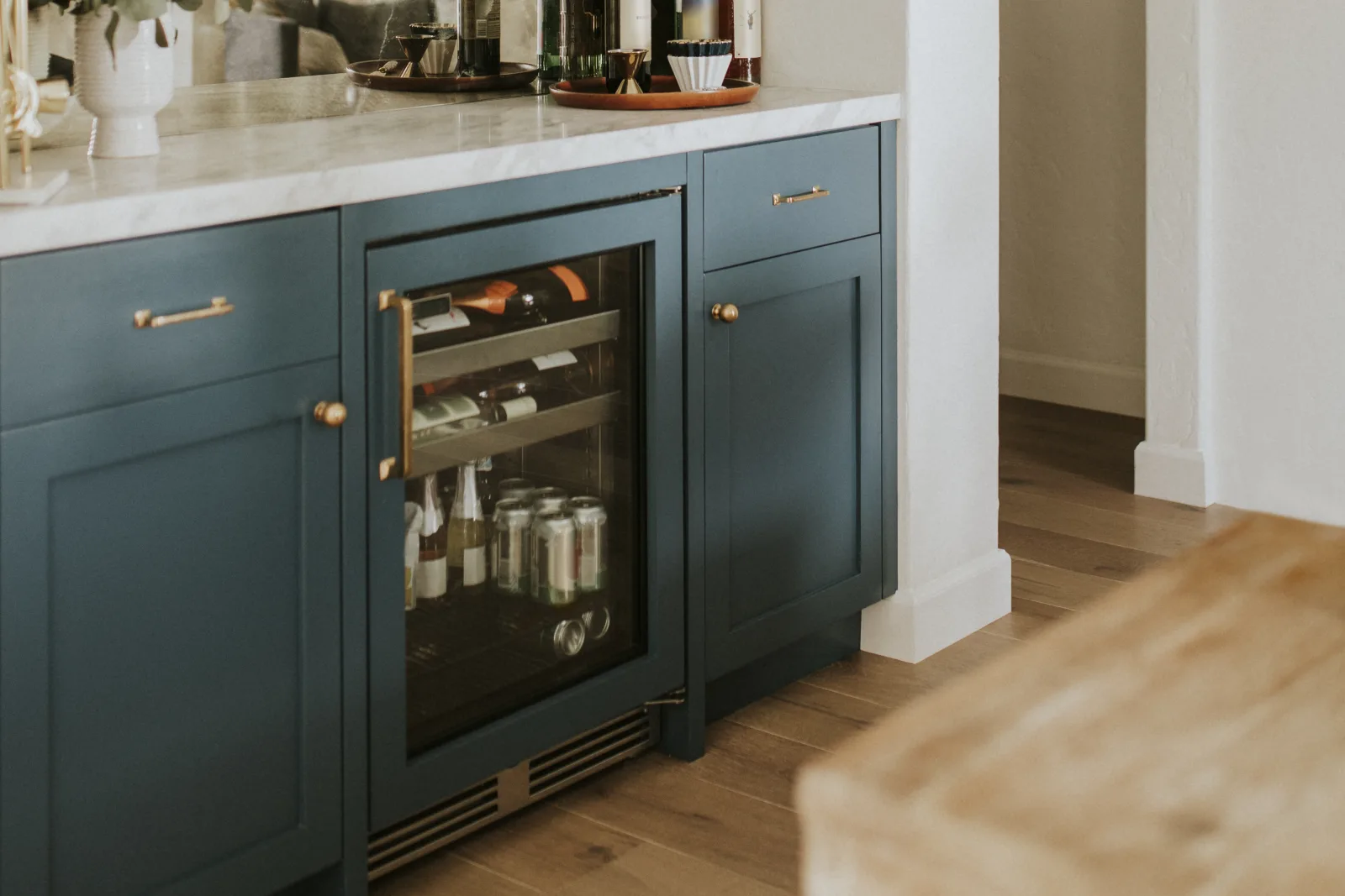 A built-in wine cooler wedged into a tight cabinet in a hot Phoenix kitchen with the front vent partly blocked, showing the desert heat and airflow stress that makes wine coolers fail early.