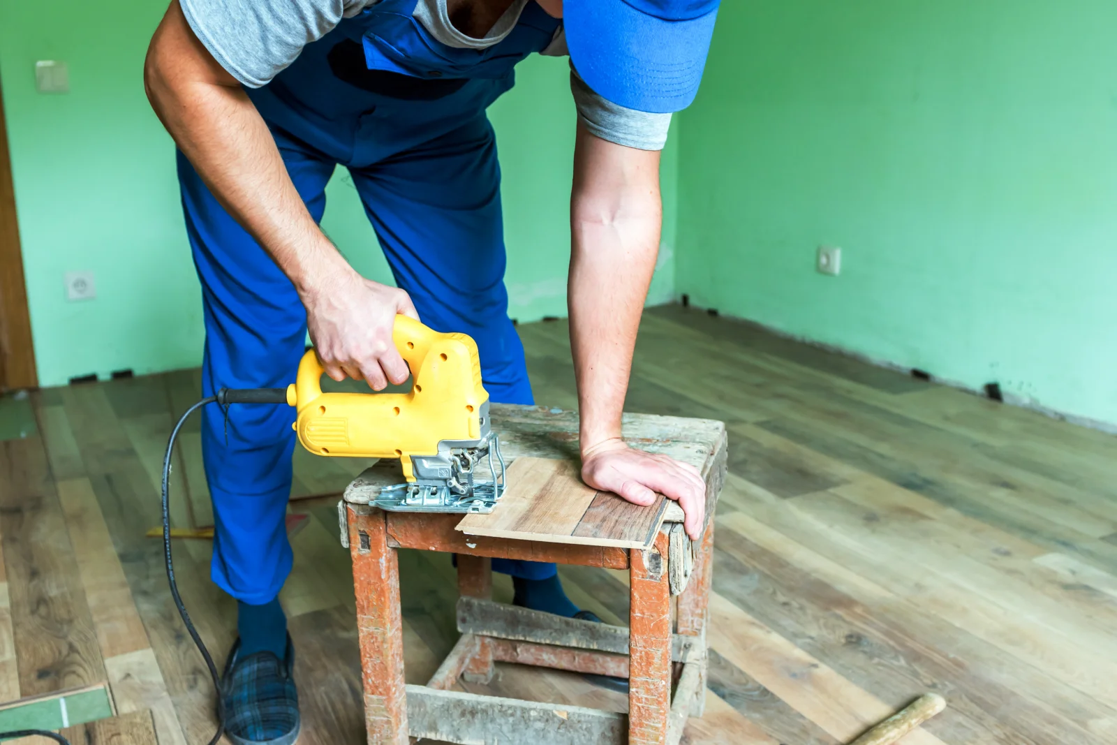 wood-floor-installation-phoenix-installer-cutting-plank-fit A wood flooring installer in coveralls cutting a plank to fit during a Phoenix wood floor installation.
