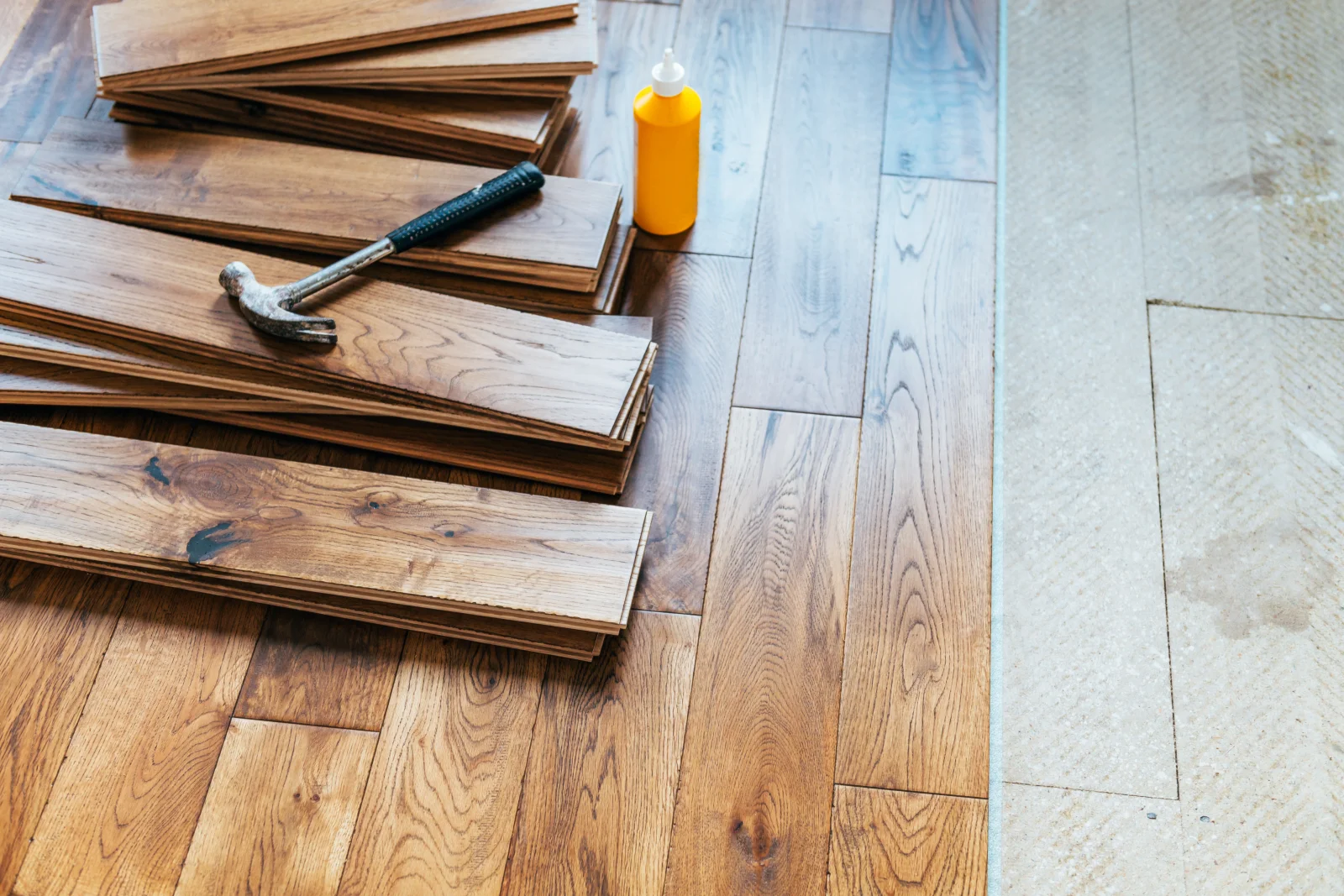 wood-floor-installation-phoenix-moisture-barrier-subfloor-prep Wood flooring planks staged on a concrete slab subfloor with a moisture barrier during a Phoenix installation.