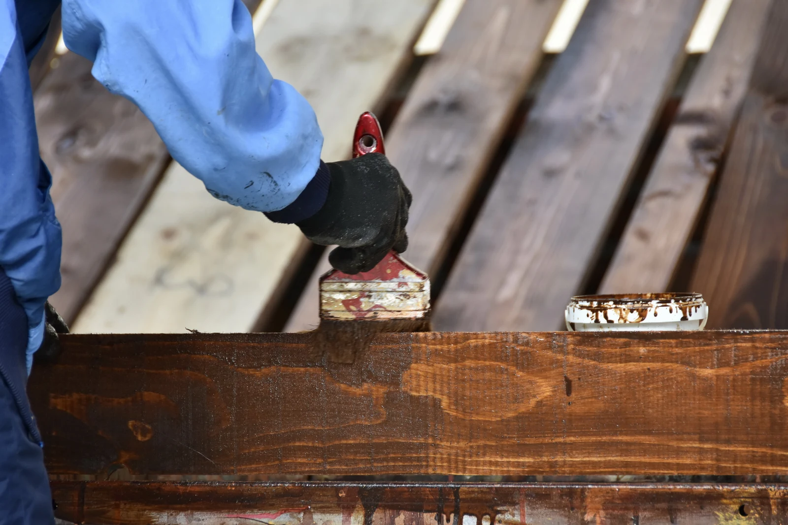 wood-staining-phoenix-beam-detail A professional applying rich wood stain to a pergola beam with a paintbrush.